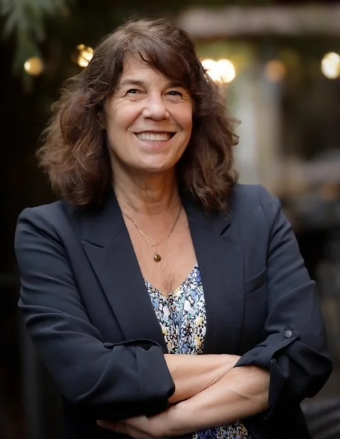 Sharon Meieran smiling at camera, arms crossed.