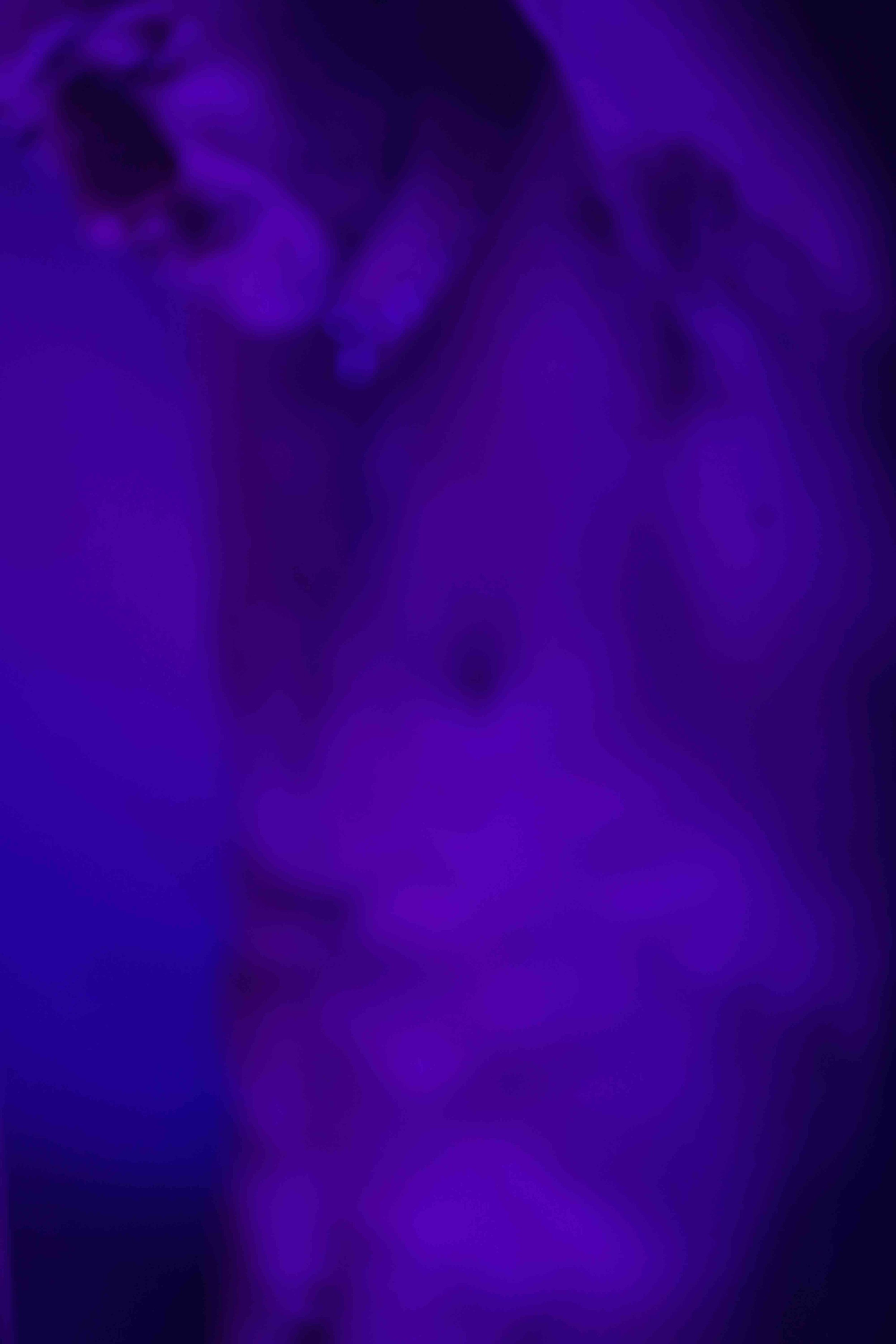 Abstract image with purple and blue hues, with a vertical streak of light in the center.