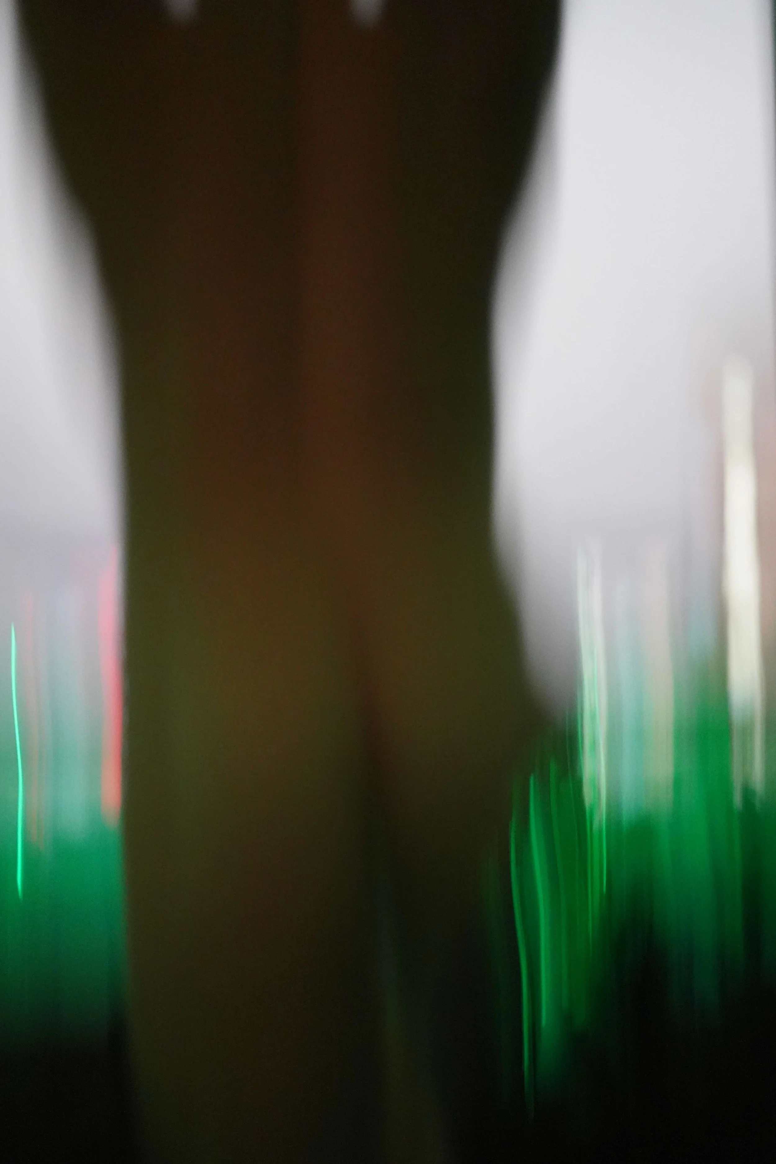 Blurred abstract image with green, red, and white lights, and dark central area.