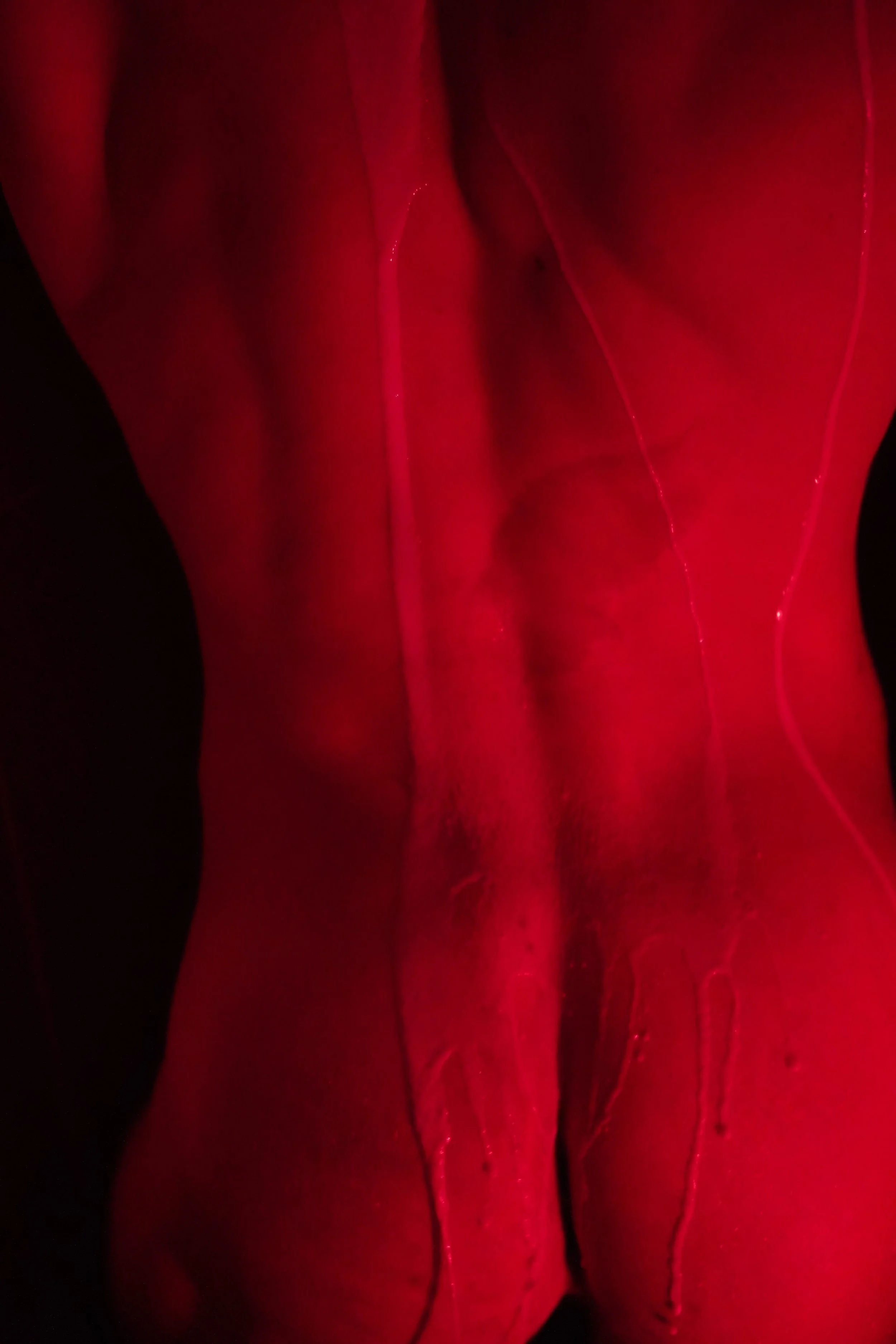 Close-up of a person with glowing red skin and some visible veins or streaks of red liquid.