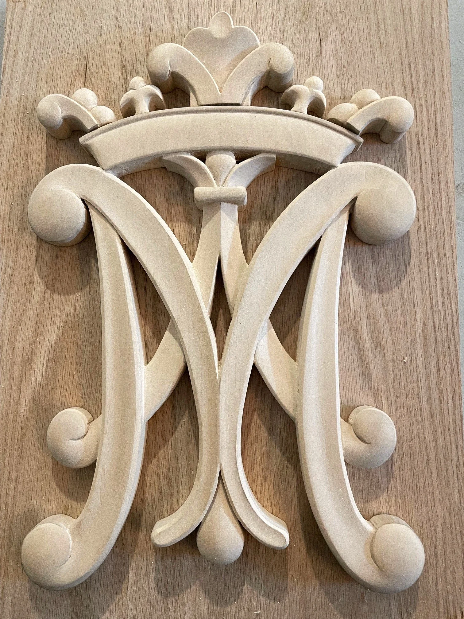 Cream-colored wooden decorative piece with ornate scrollwork and floral elements, possibly part of a furniture or architectural detail.