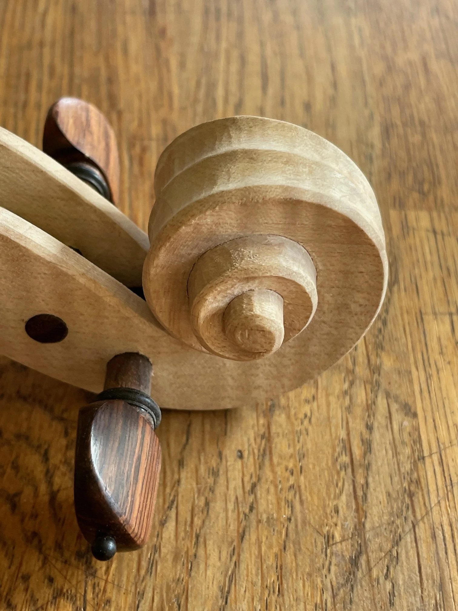 Close-up of a wooden spinning top toy with a carved spiral design, placed on a wooden surface.