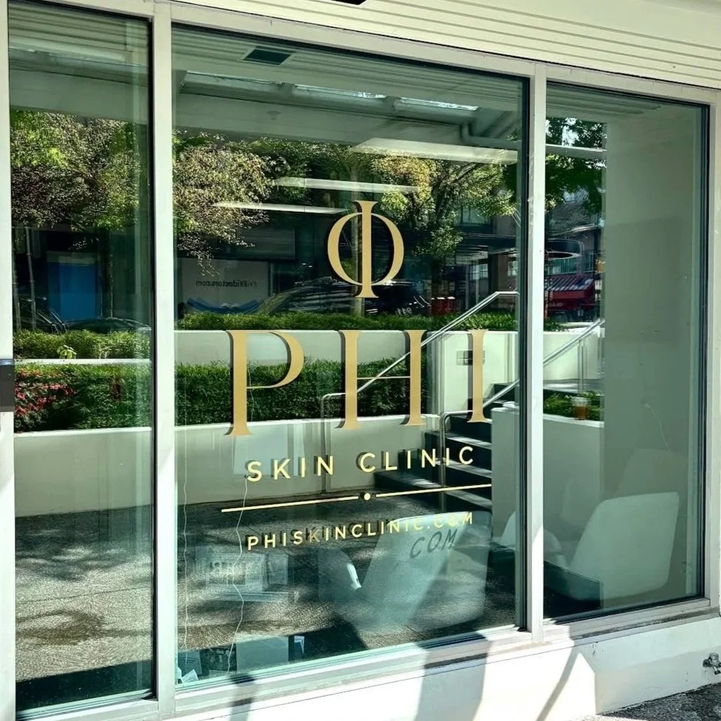 Glass entrance of Phi Skin Clinic in Vancouver displaying the clinic logo and website.