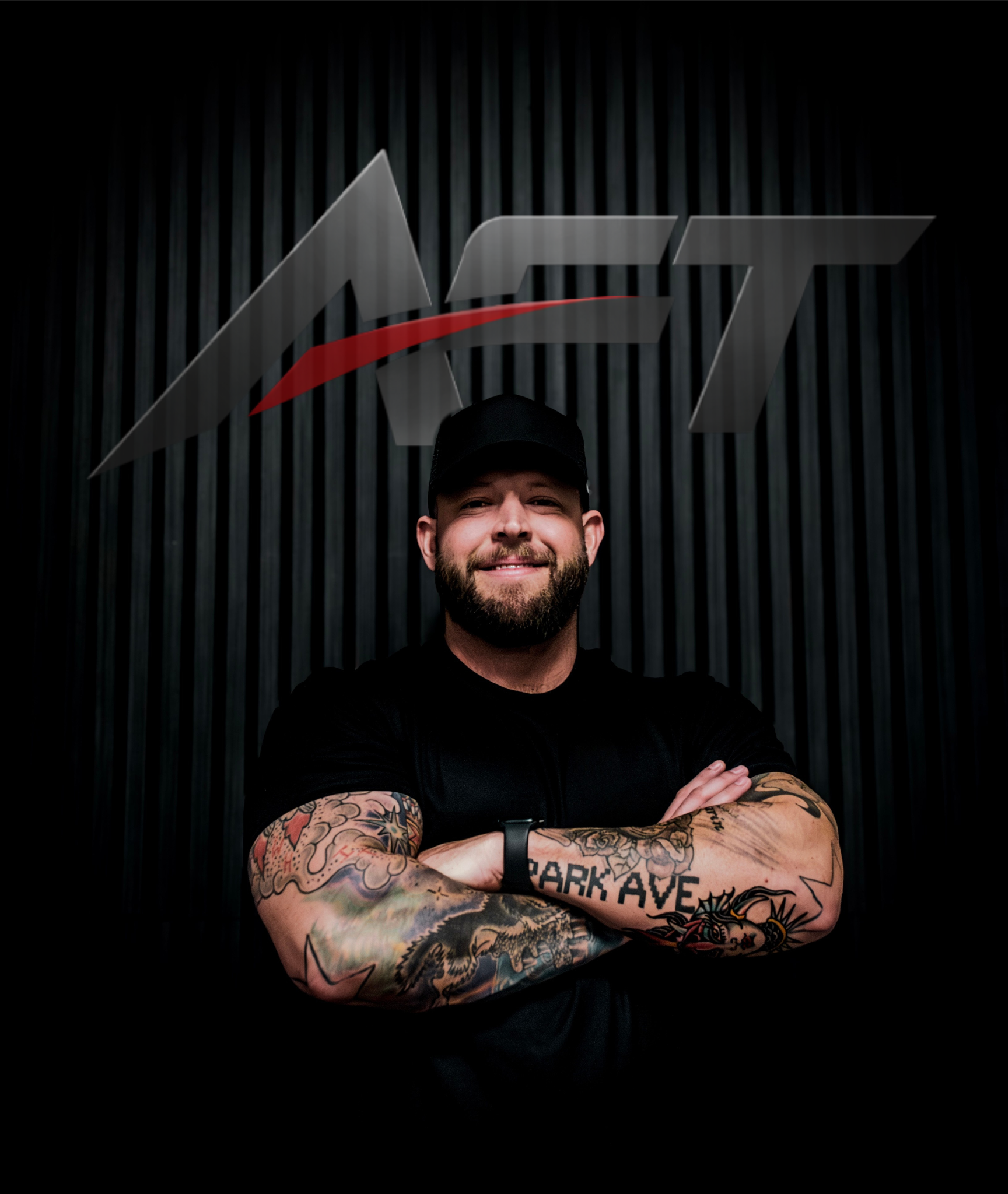 Man with tattoos smiling and crossing arms in front of a wall with a large 'ACT' logo