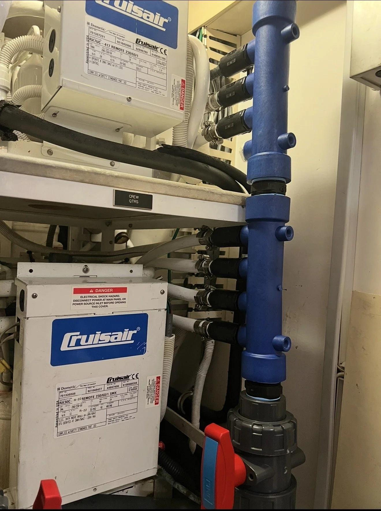 Mechanical and electrical equipment with white and blue appliances, pipes, and wires in an industrial setting.