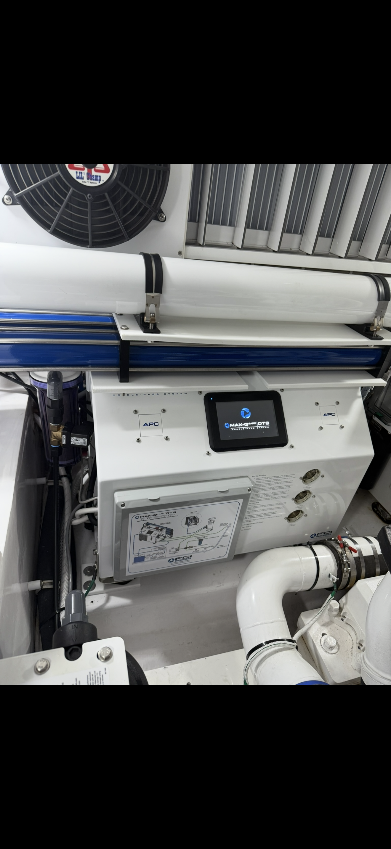 Close-up of a white industrial machine with a digital display labeled "MAX-Q™ DTS,” pipes, and a black fan at the top.