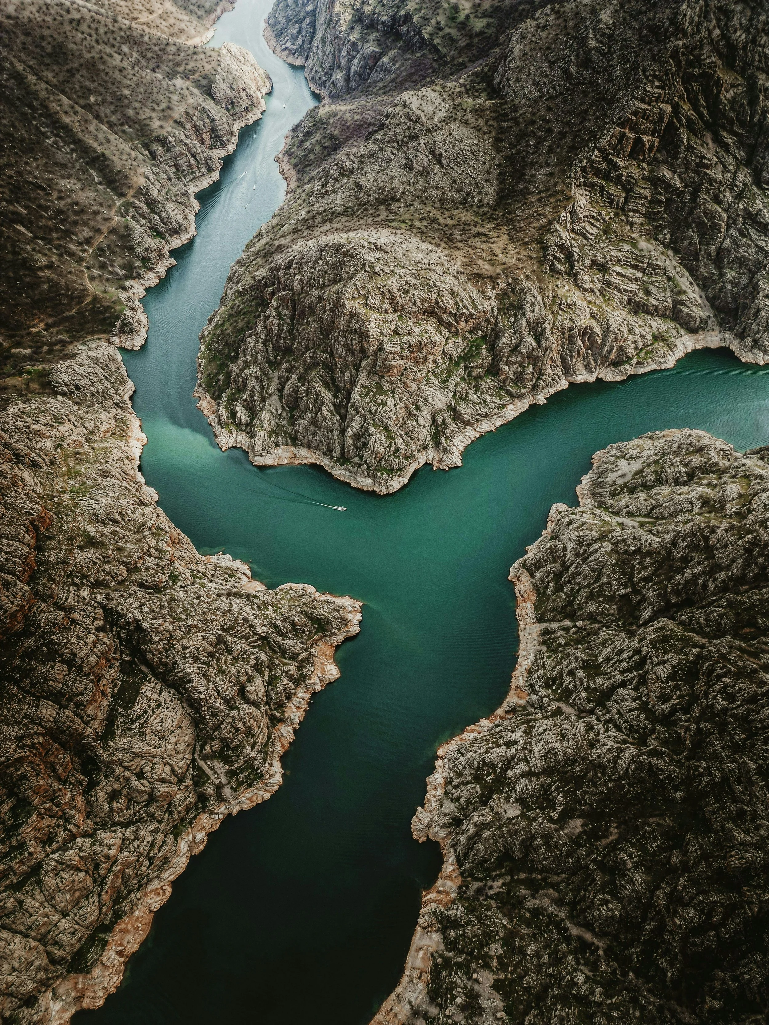Aerial view of a winding river flowing through a canyon with rugged, rocky cliffs and sparse vegetation. Describing the journey that is undertaken during the year long immersion programmes at CONOS.