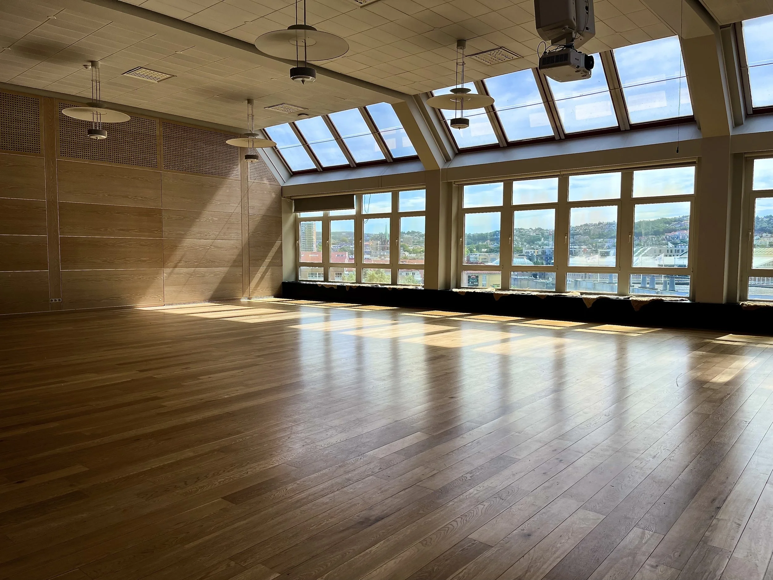 The Glass Garden, a beautiful, large interior event space for rent in central Oslo with big windows allowing a lot of natural daylight, wooden flooring, and modern ceiling lights.