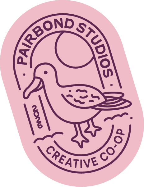 Pink oval logo with purple outline featuring an albatross illustration, surrounded by text reading 'Pairbond Studios' at the top and 'Creative Co-op' at the bottom, with a purple circle sun or moon in the background.