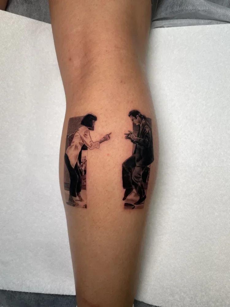 Tattoo of two women sitting and pointing at each other on a person's lower leg.