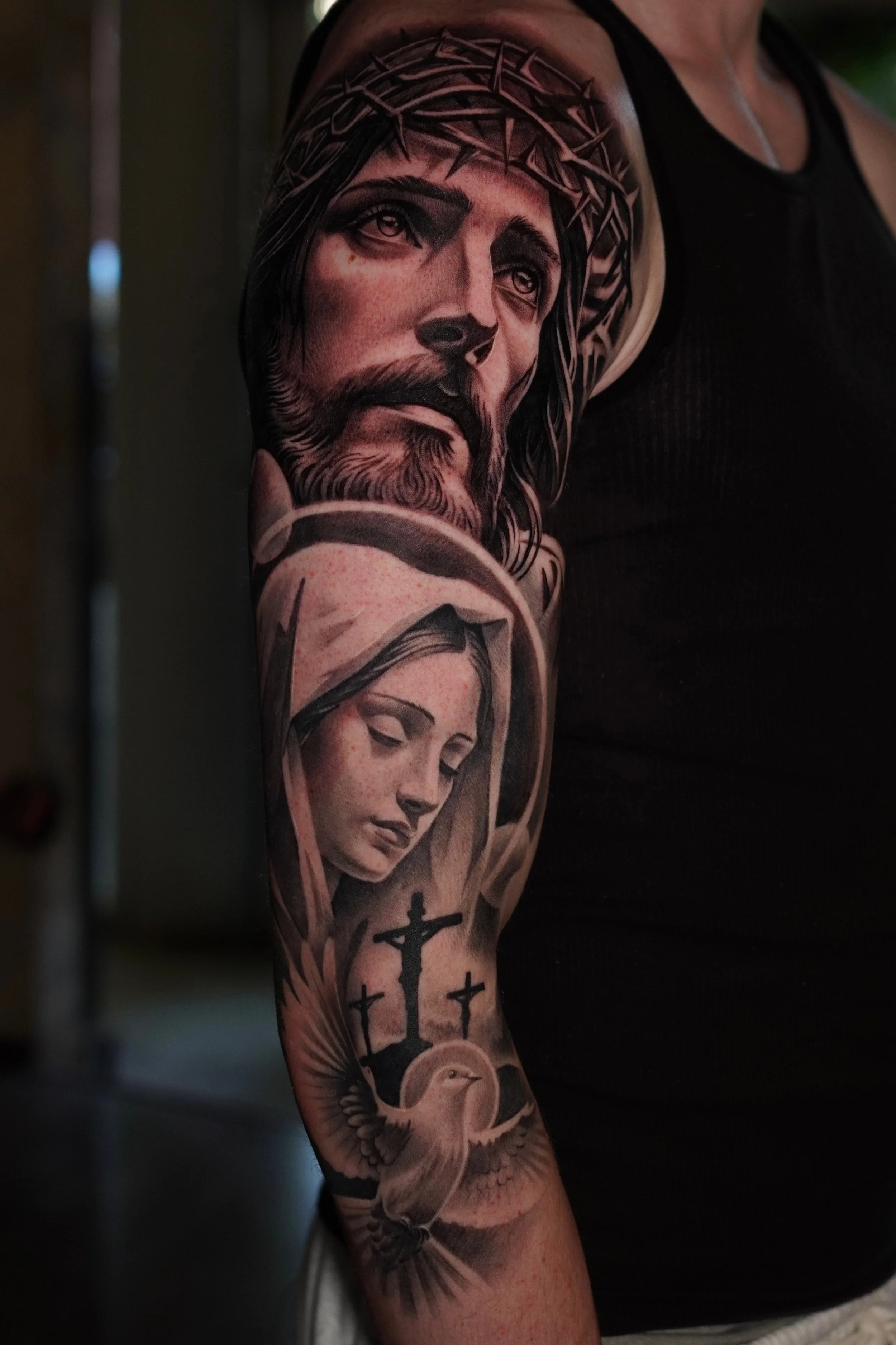 Tattoo of Jesus Christ with a crown of thorns on the person's upper arm and shoulder.