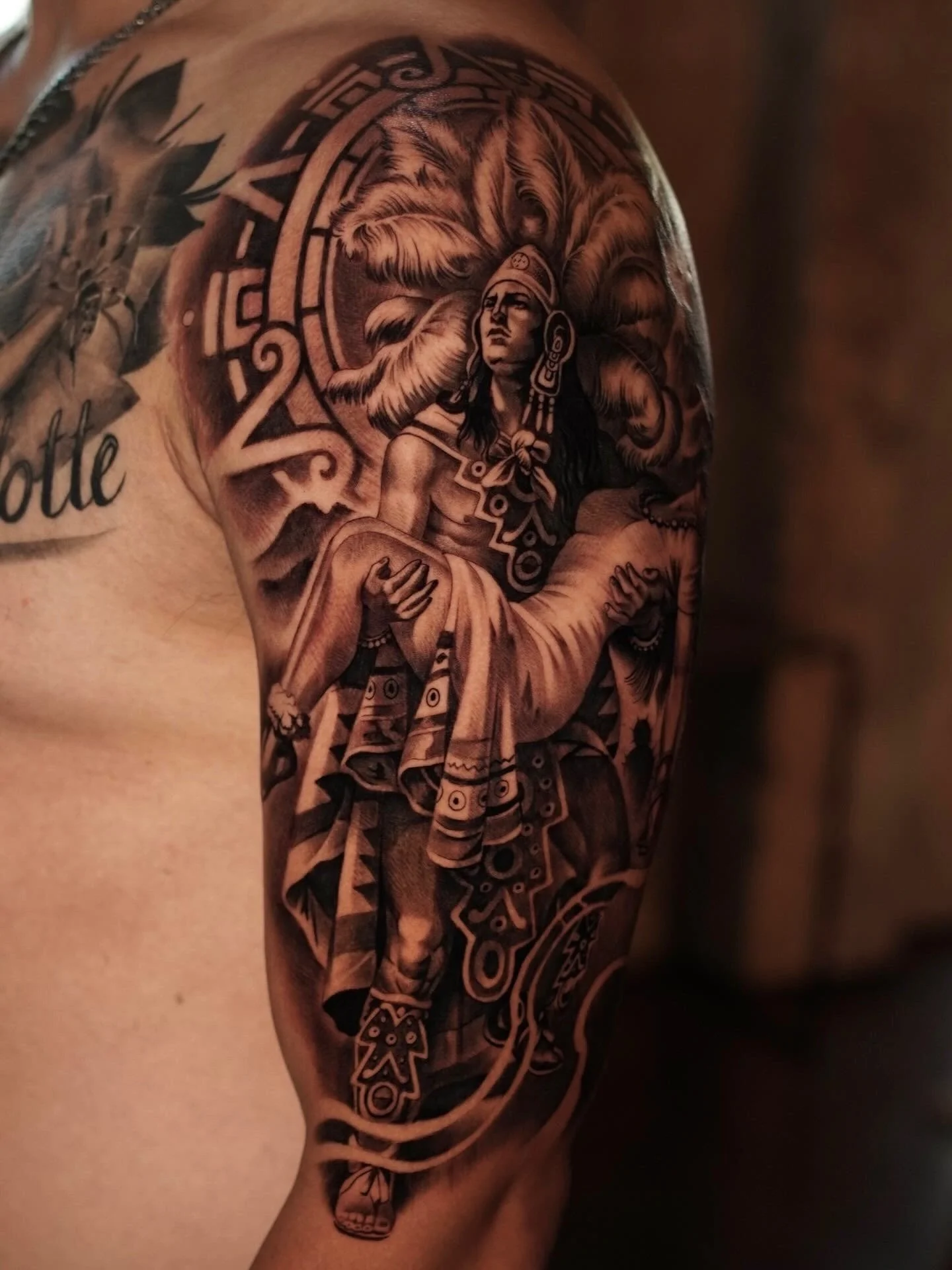 Tattoo of a Native American woman with a feathered headdress on the upper arm.