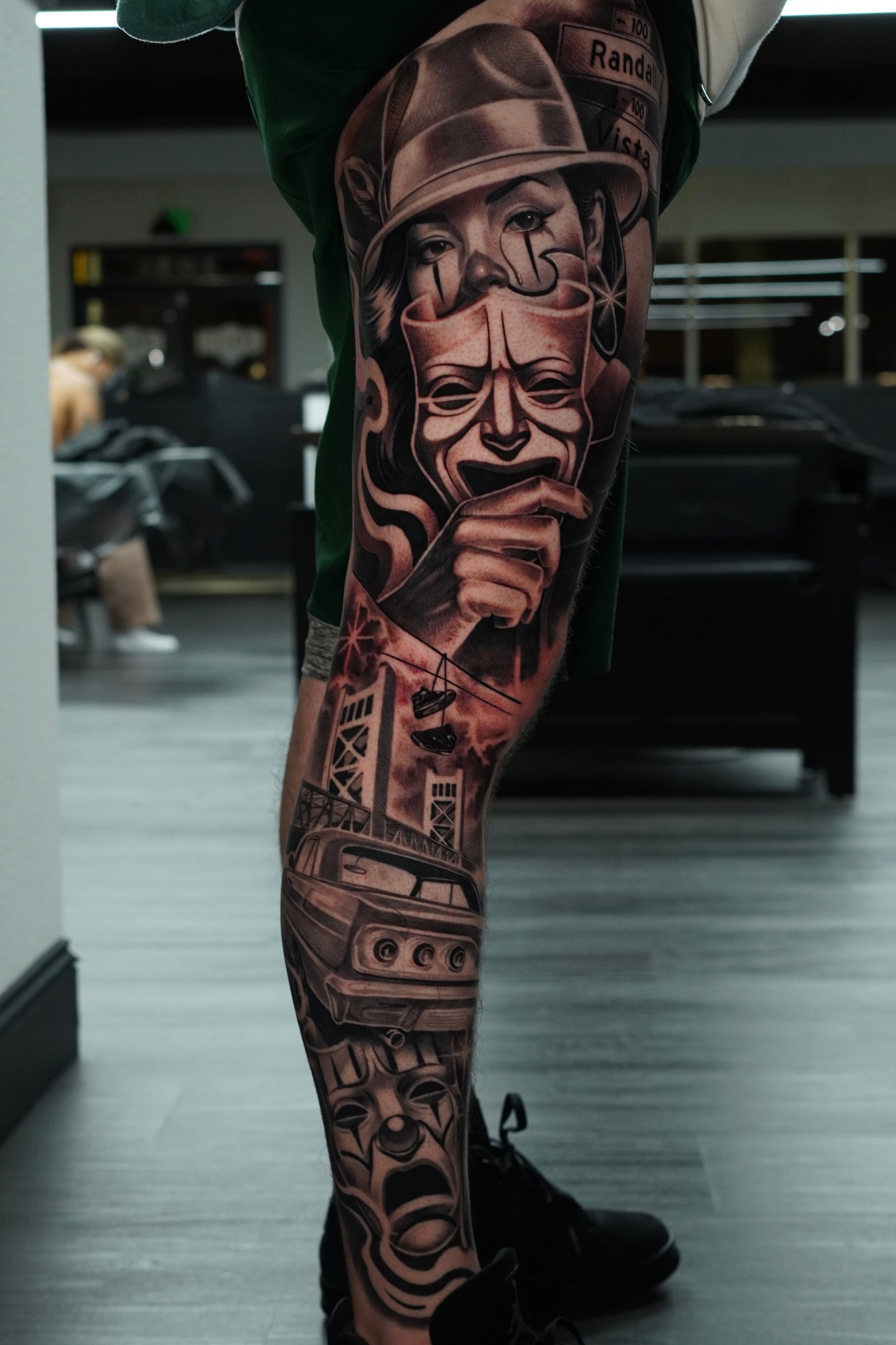 Full sleeve tattoo on a person's arm featuring a collage of faces, a vintage car, and abstract designs.
