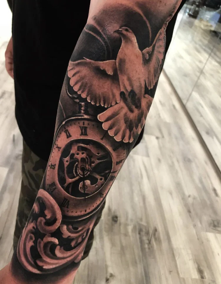 Tattoo featuring a dove in flight above a pocket watch with Roman numerals on the arm.