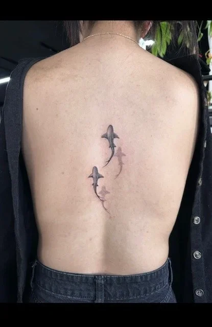 Tattoo of three sharks swimming down the back.
