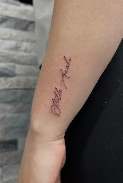 Tattoo reading 'Attle Ashki' on a person's forearm.