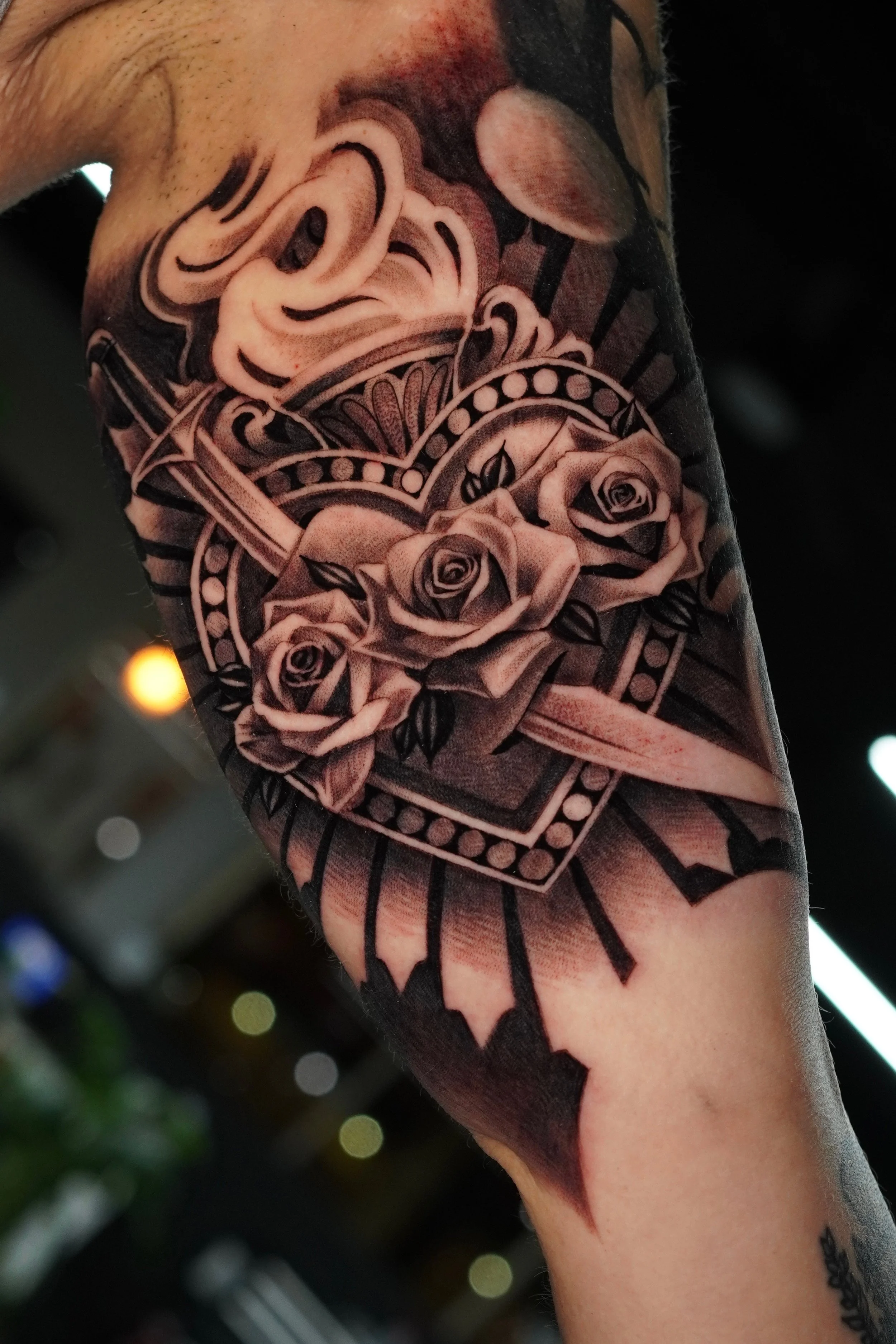 Tattoo of a skull surrounded by roses on a person's arm.