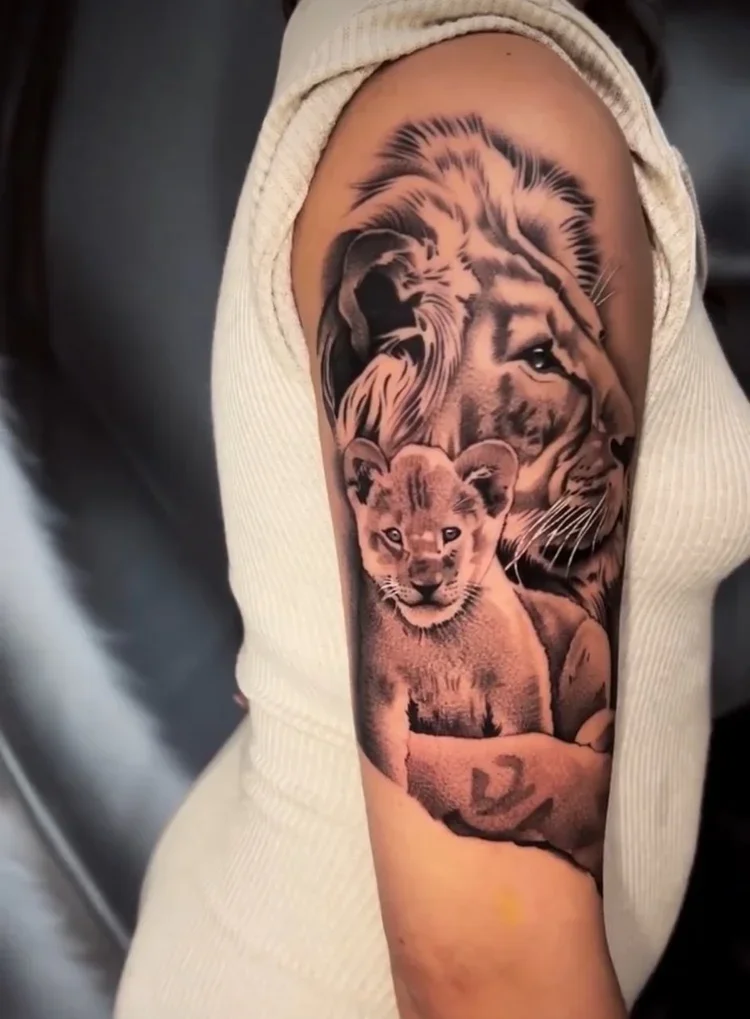 Tattoo of a lion and a lion cub on a person's upper arm.