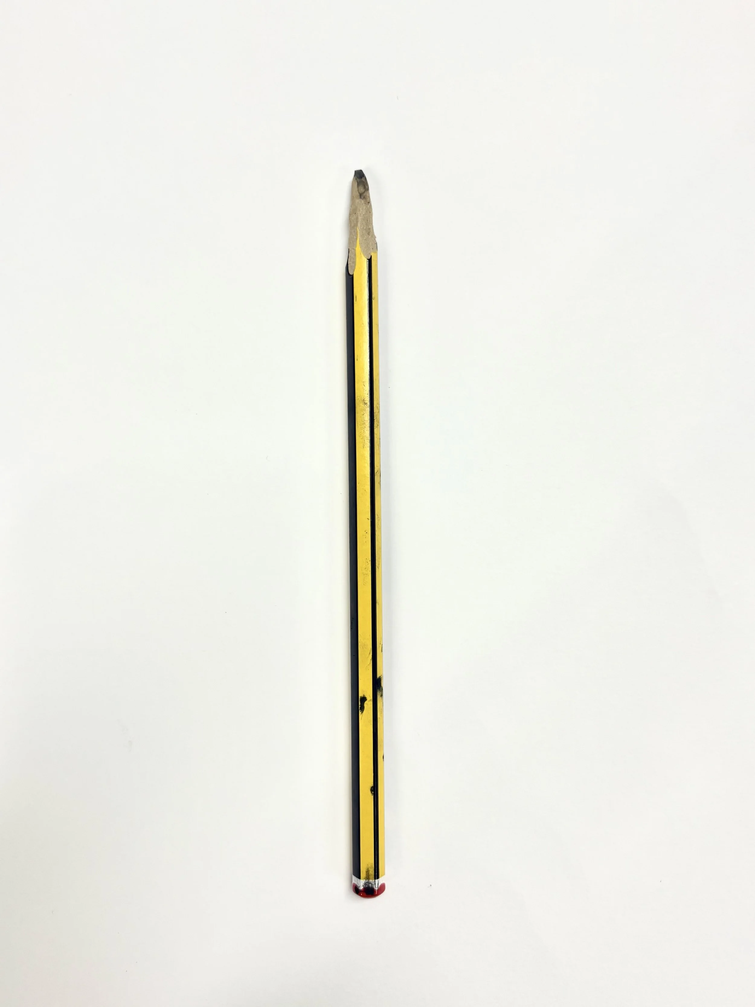 A wooden pencil with yellow and black coloring, broken at the sharpened tip, placed vertically on a white background.
