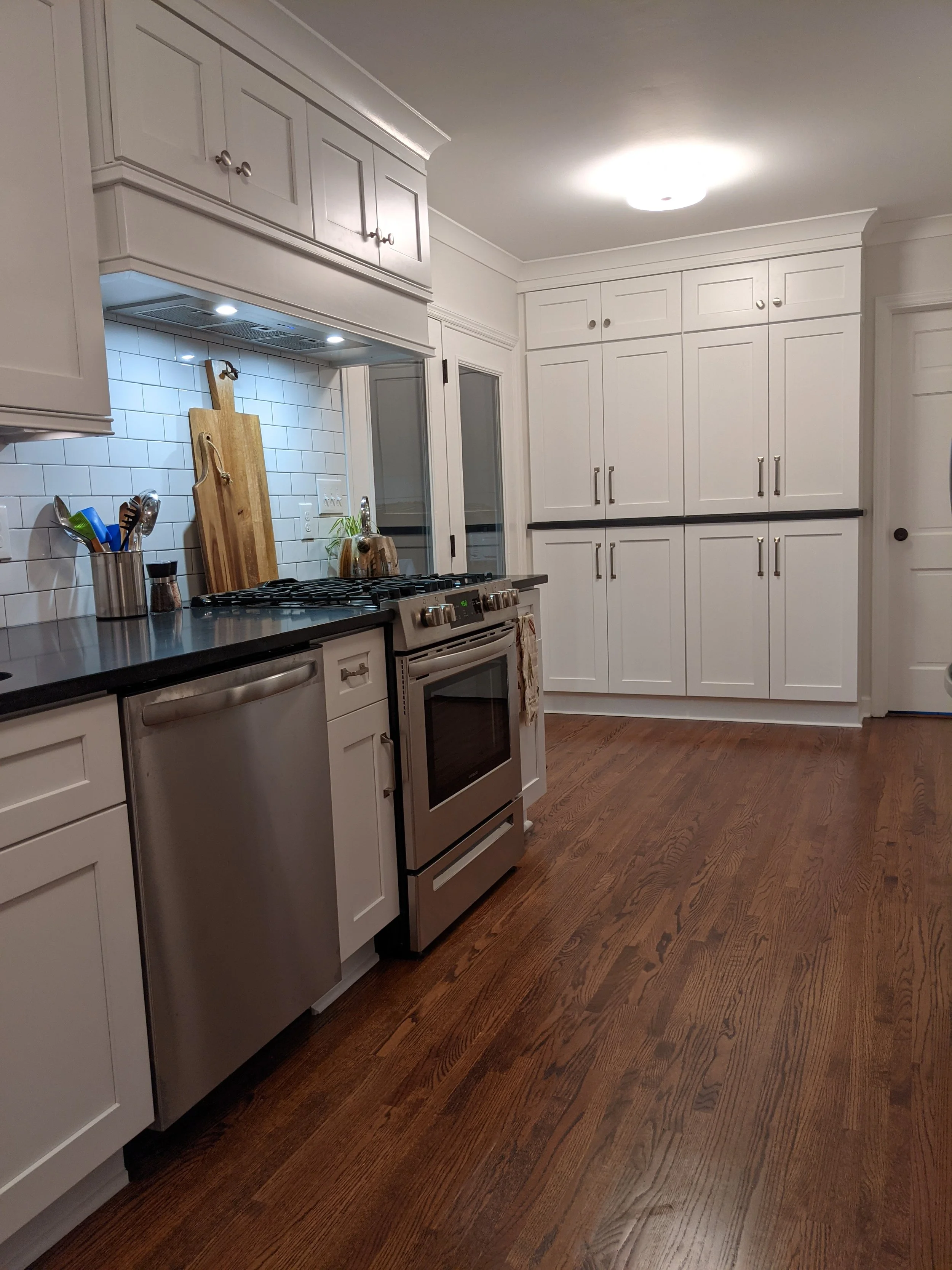 Gatepost kitchen looking toward custom pantry, White Shaker Cabinets, Custom Range Hood, Quartz Countertop, Subway Tile Backsplash.