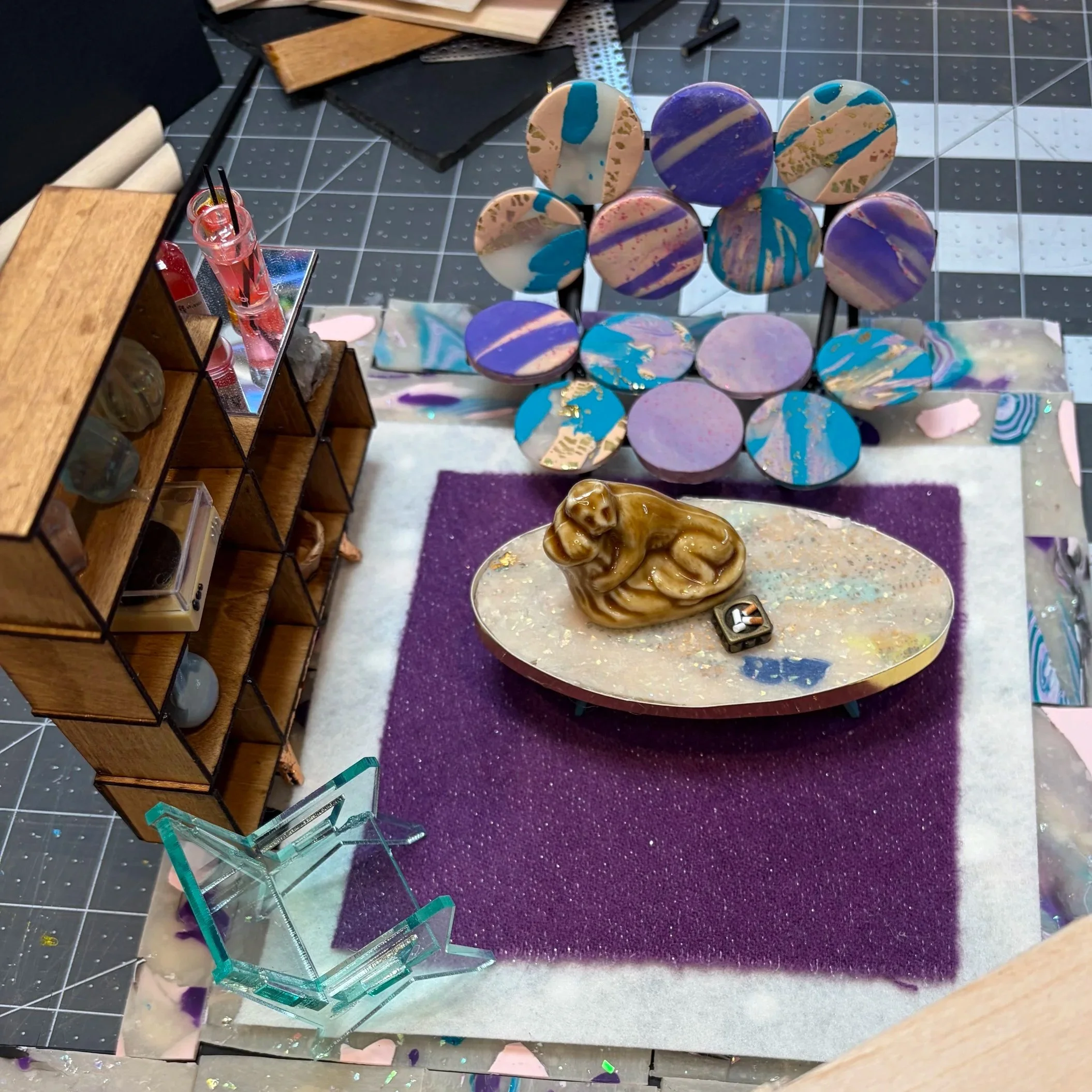 Display of colorful marbled circular art pieces on a black stand in an art studio, with glass display cases and art materials nearby.