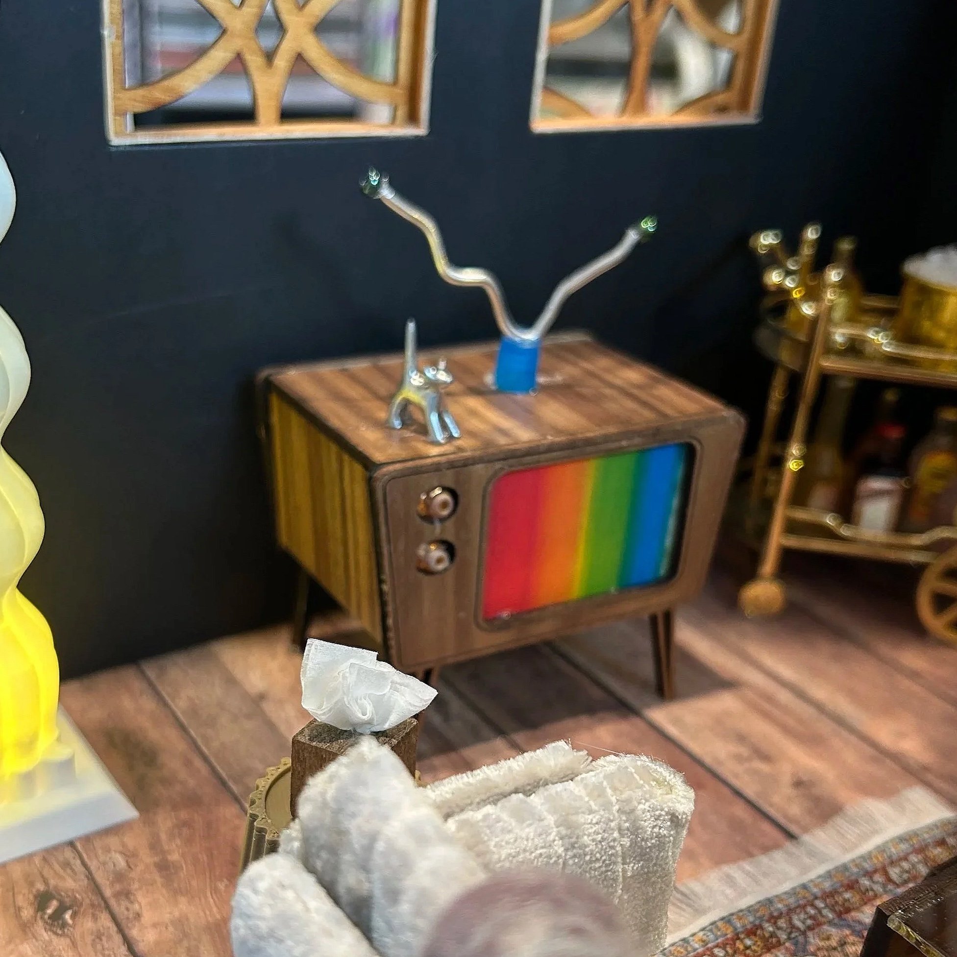 Close-up of a decorative object with stones and a gold-colored ornament on a wooden surface, with other furniture and decorative items in the background.
