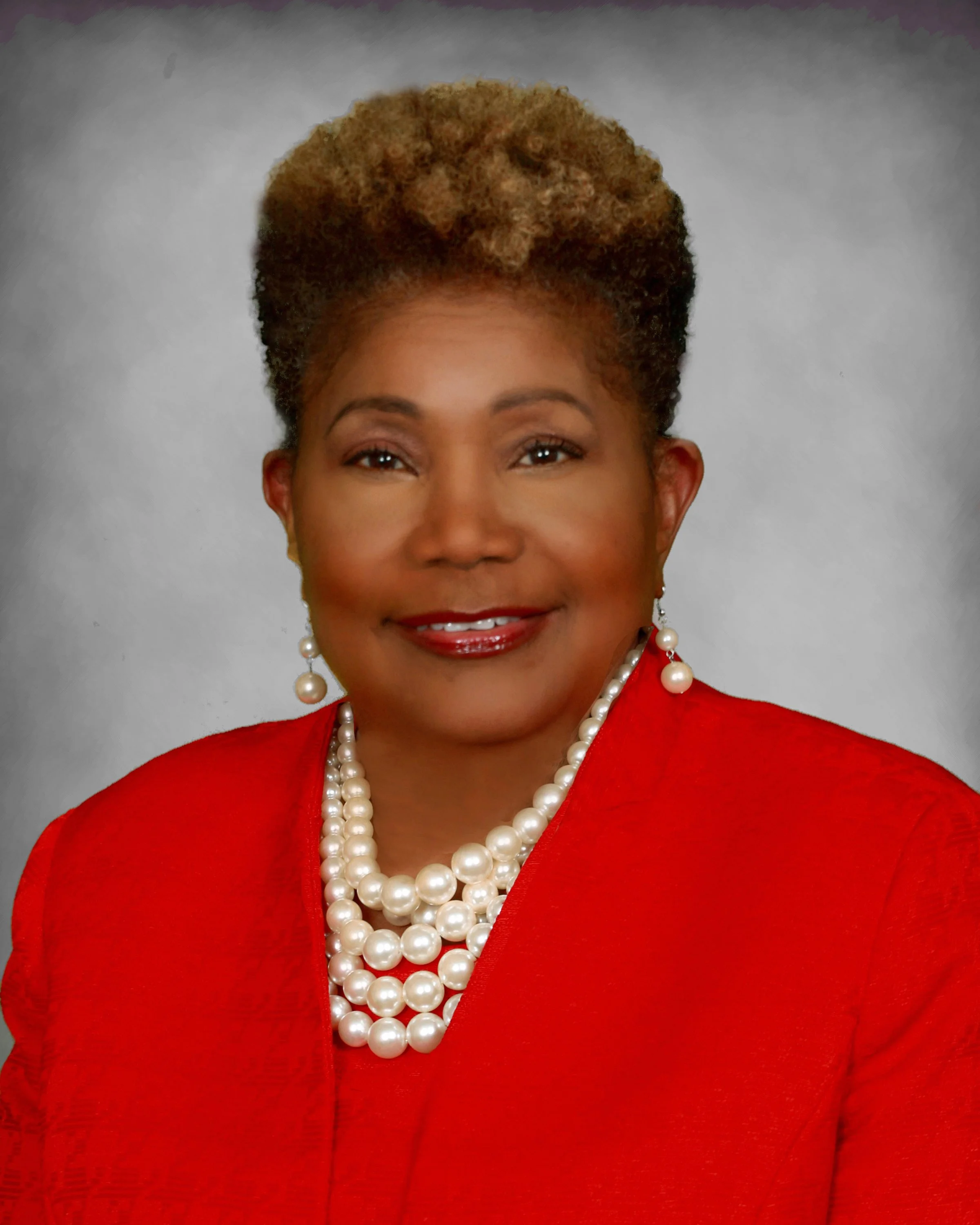 Headshot of Soror Lorraine Coleman in red blazer and pearl necklace
