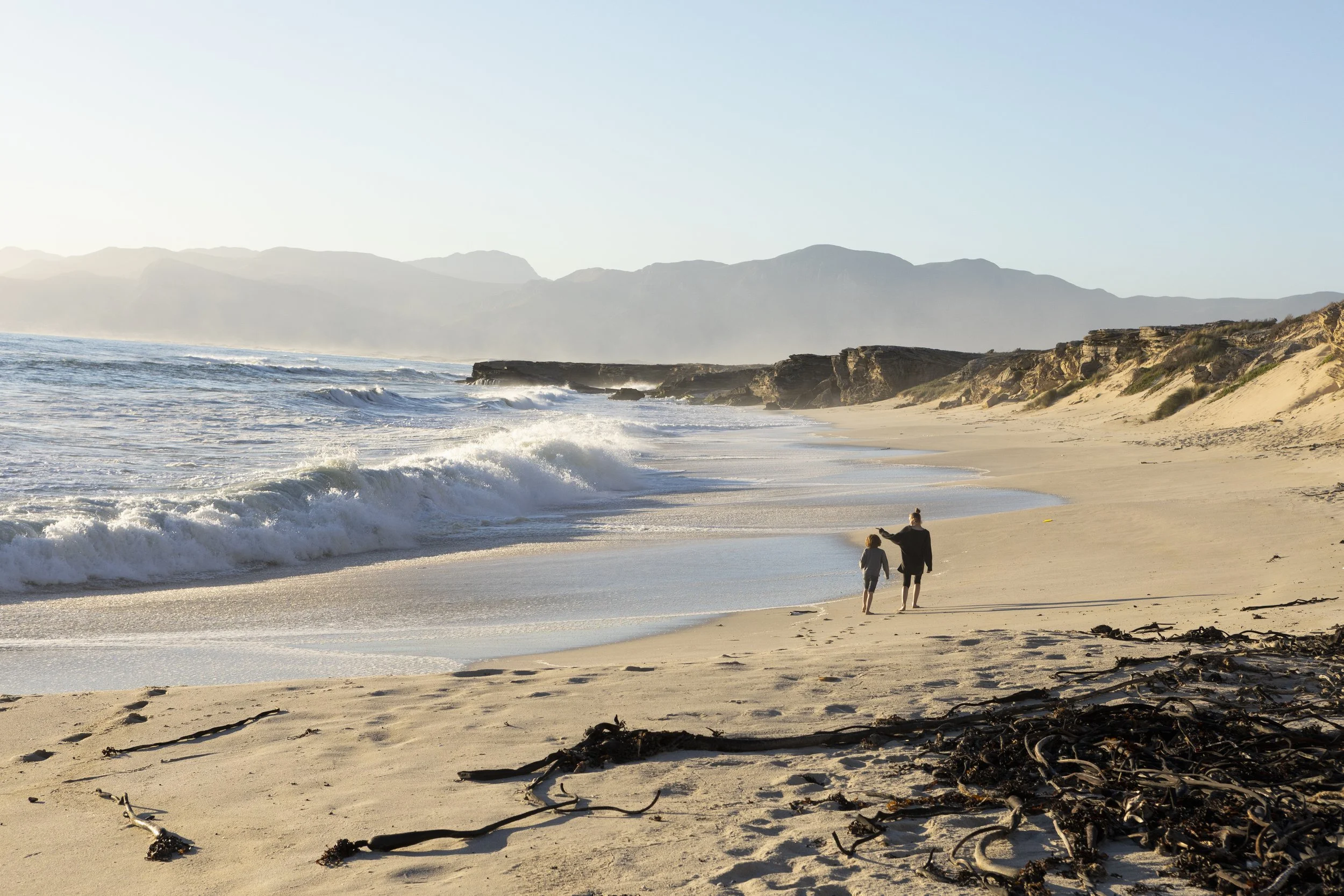 two-people-walking-along-a-sandy-beach-a-teenager-2026-03-25-02-49-56-utc.jpg