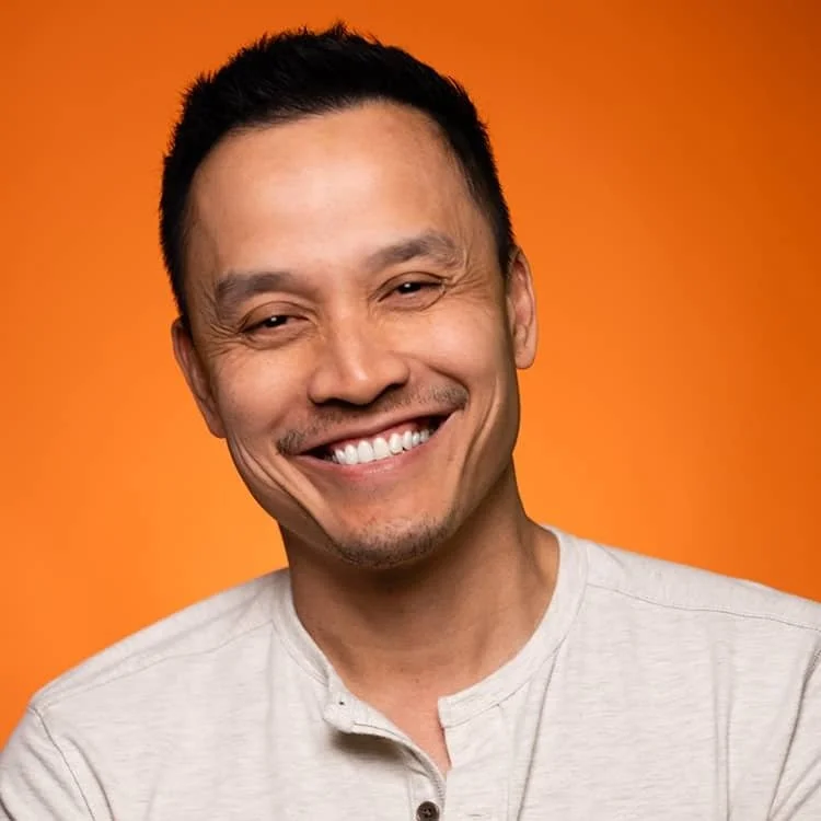 Smiling man with short black hair against orange background