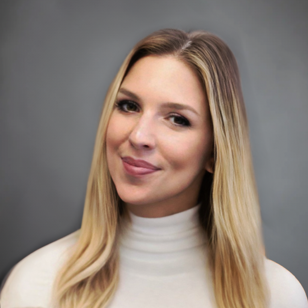 Portrait of a woman with long blonde hair wearing a white turtleneck, smiling slightly, against a gray background.