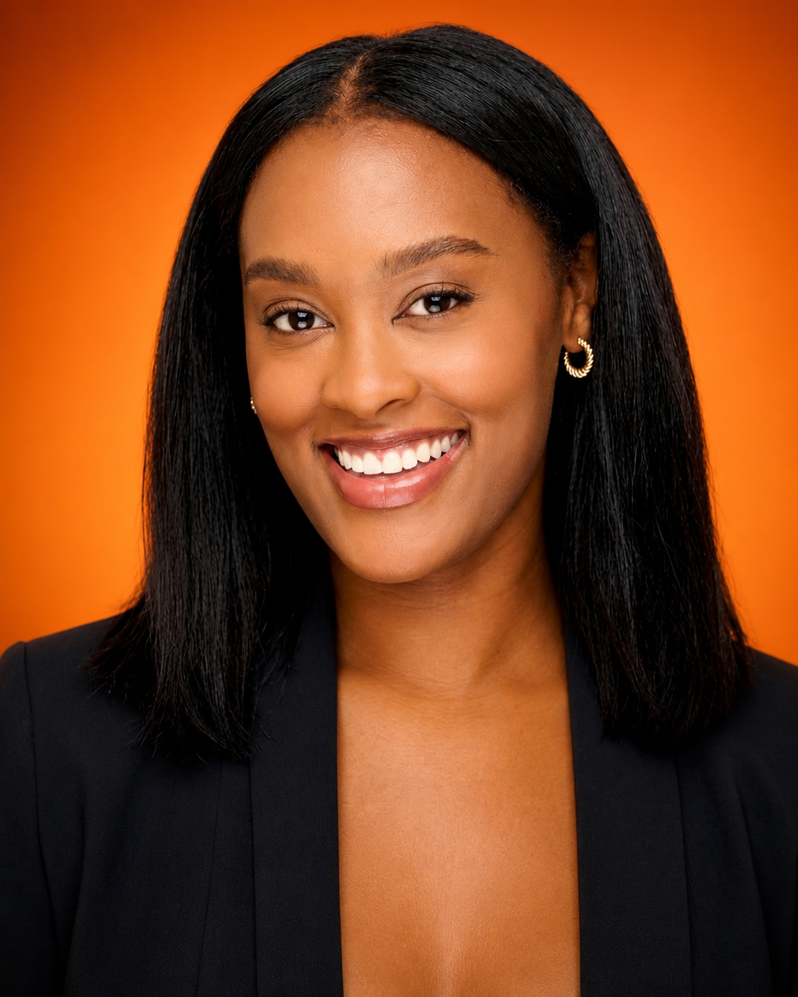 A smiling woman with medium-dark skin, black straight hair, gold hoop earrings, wearing a black blazer, against an orange background.