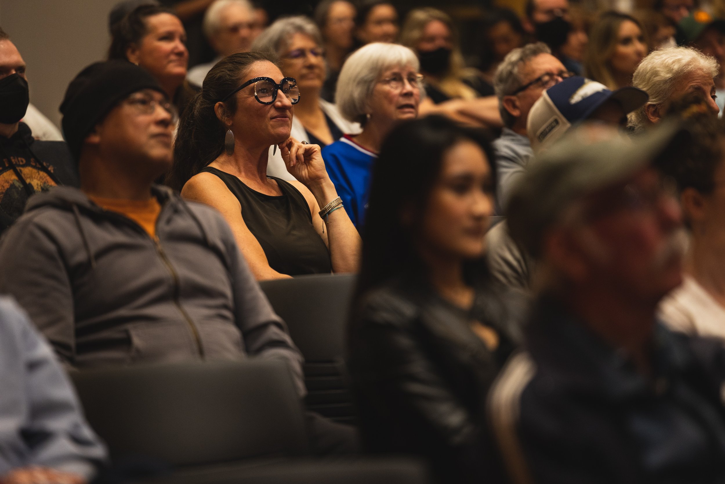 Audience members attending an event, sitting in rows, watching attentively.