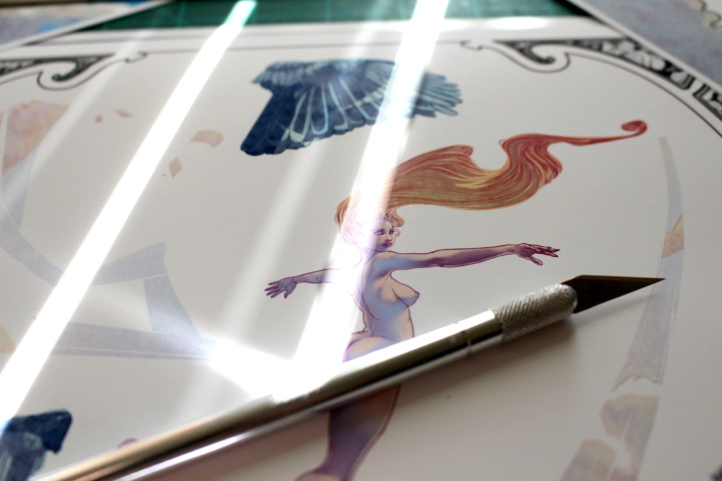A piece of artwork featuring a stylized woman with long flowing red hair and a winged figure, with a decorative border at the top. The artwork is placed under bright fluorescent lighting.