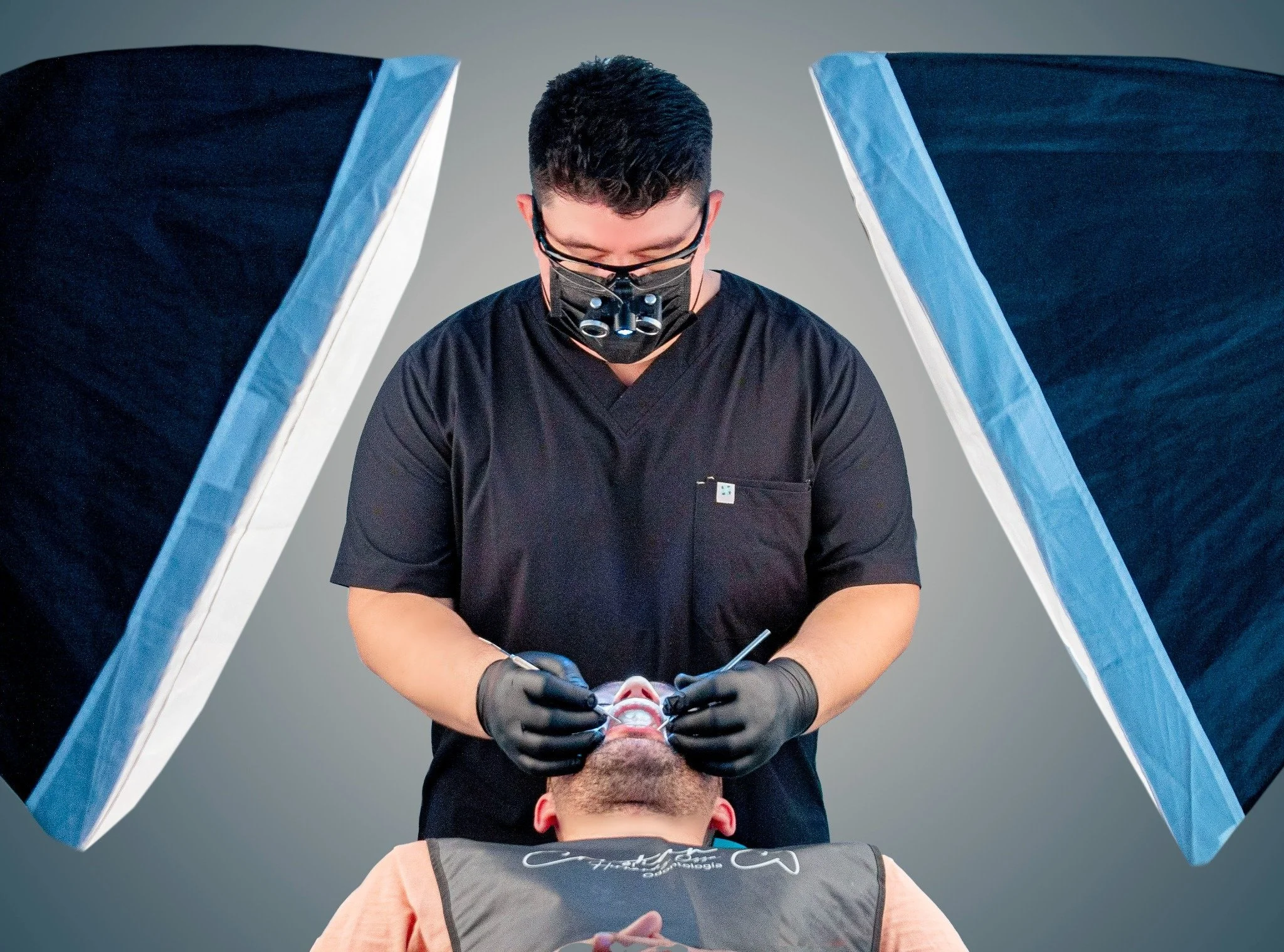 Un cirujano realizando un procedimiento en un paciente acostado. El cirujano usa gafas con lupa y guantes negros, y está concentrado en su trabajo.