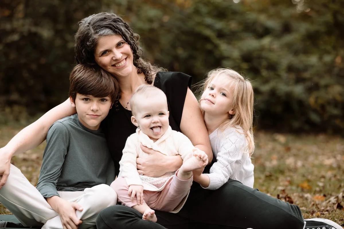 A woman with three young children in an outdoor setting.