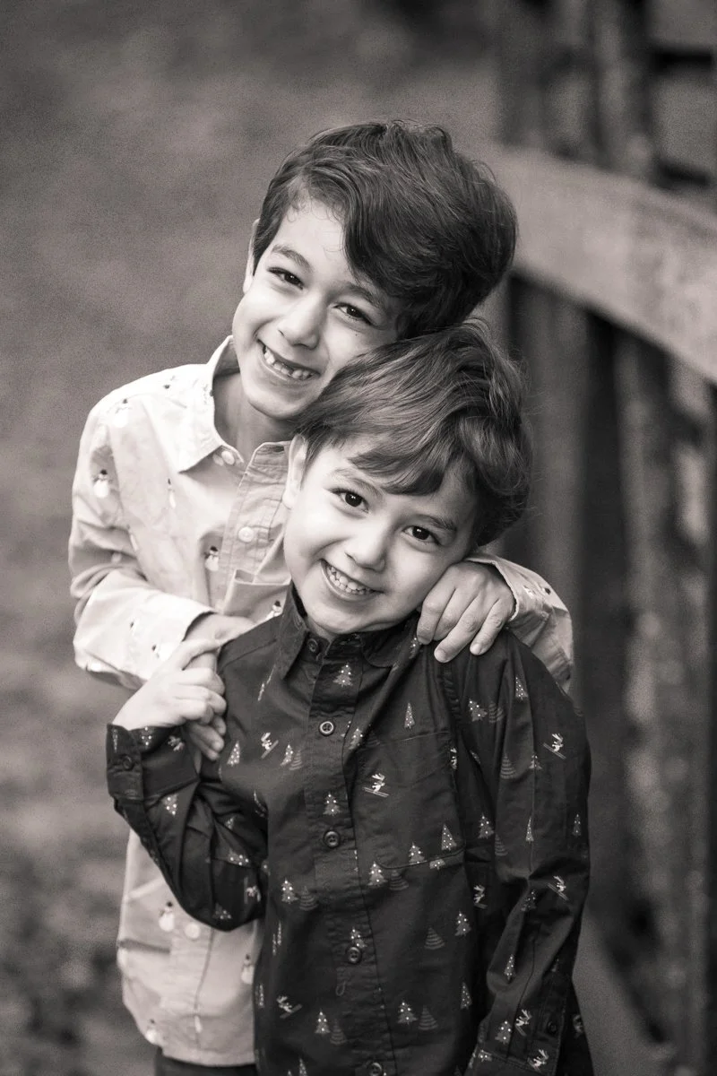 Two young boys smiling and hugging outdoors, black and white photo.