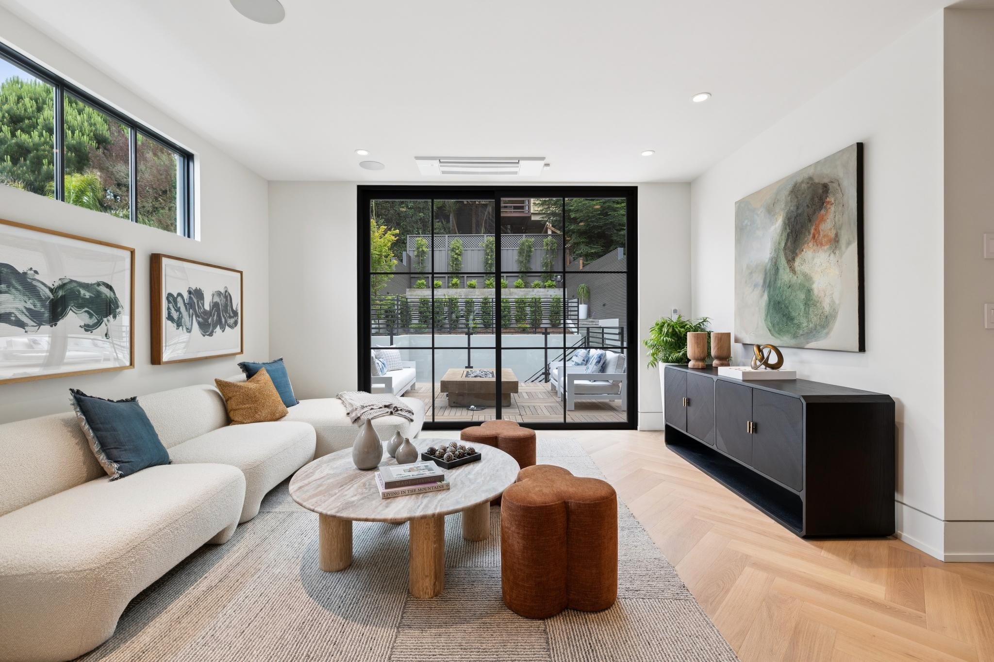 Modern living room with white sofa, abstract artwork, round coffee table, and sliding glass door opening to outdoor balcony
