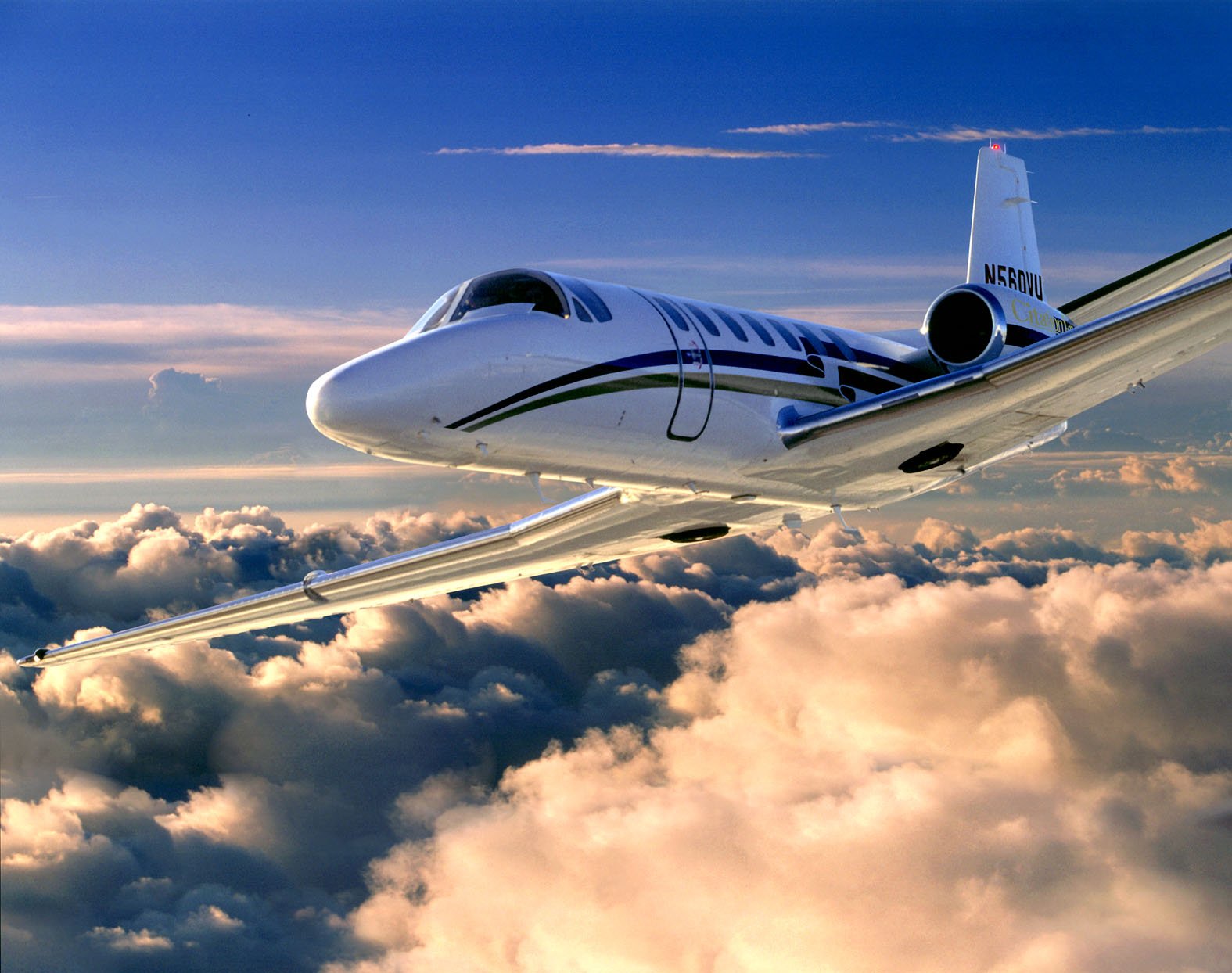 A small private jet flying above clouds during sunset or sunrise.