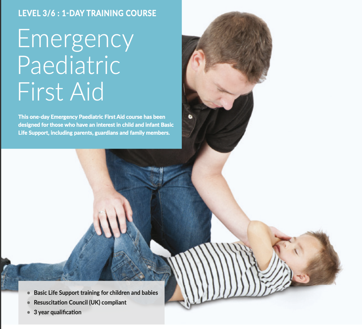 A young man performs first aid on a child lying on the ground, with the young man kneeling beside the child and holding the child's arm.