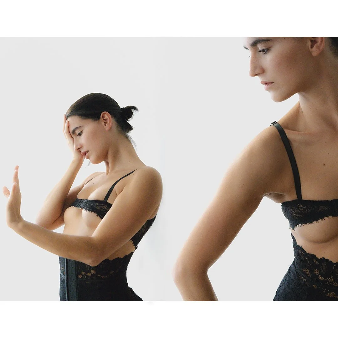 Two women in black lace lingerie, one holding her forehead and distressed, the other turned away.