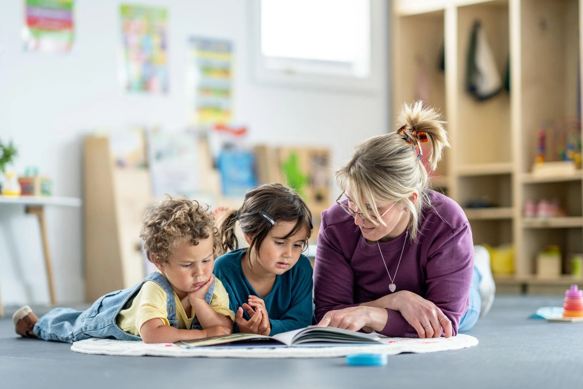 Early years practitioner reading with children in a Plymouth nursery