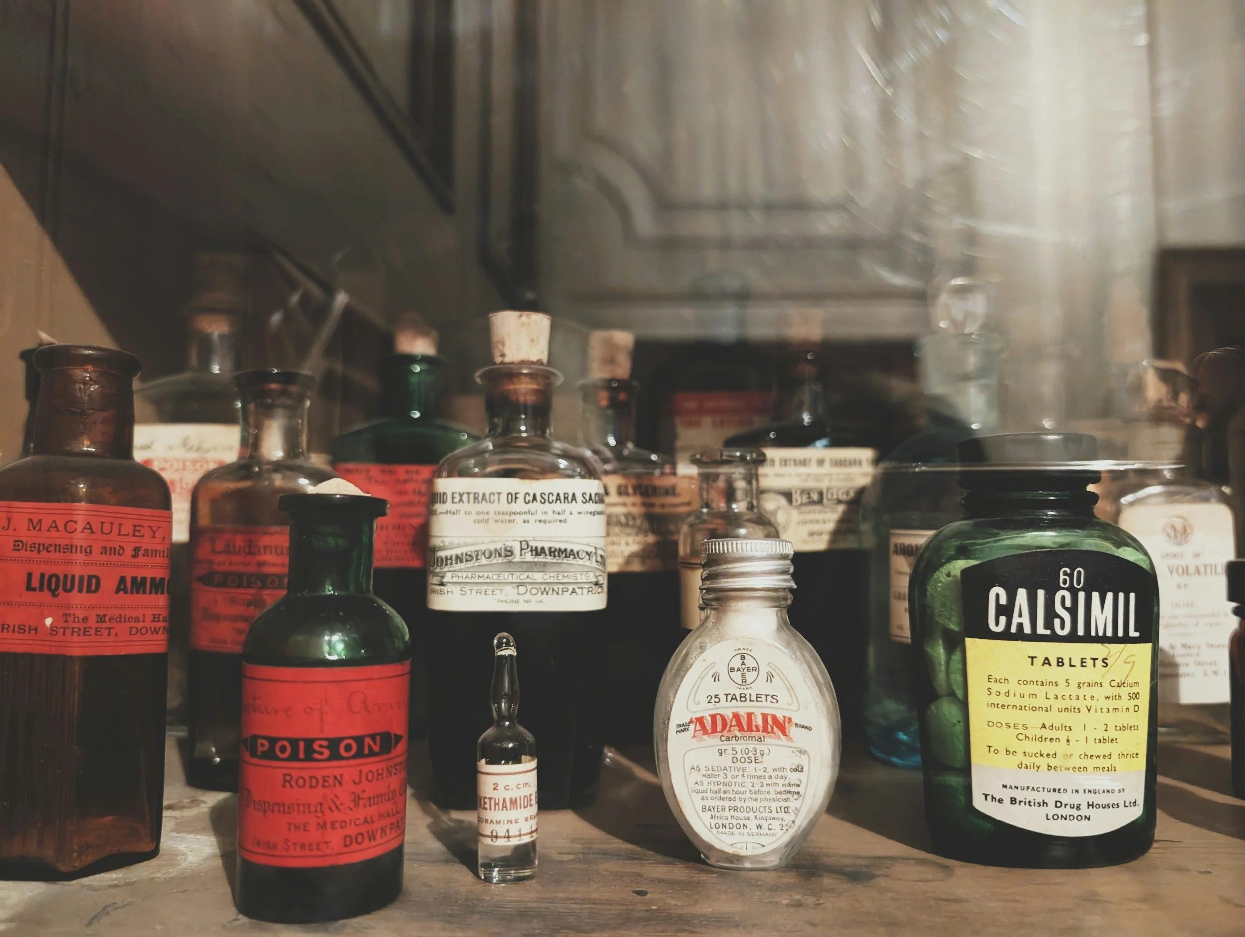 Collection of vintage medicine bottles and boxes on a wooden shelf.