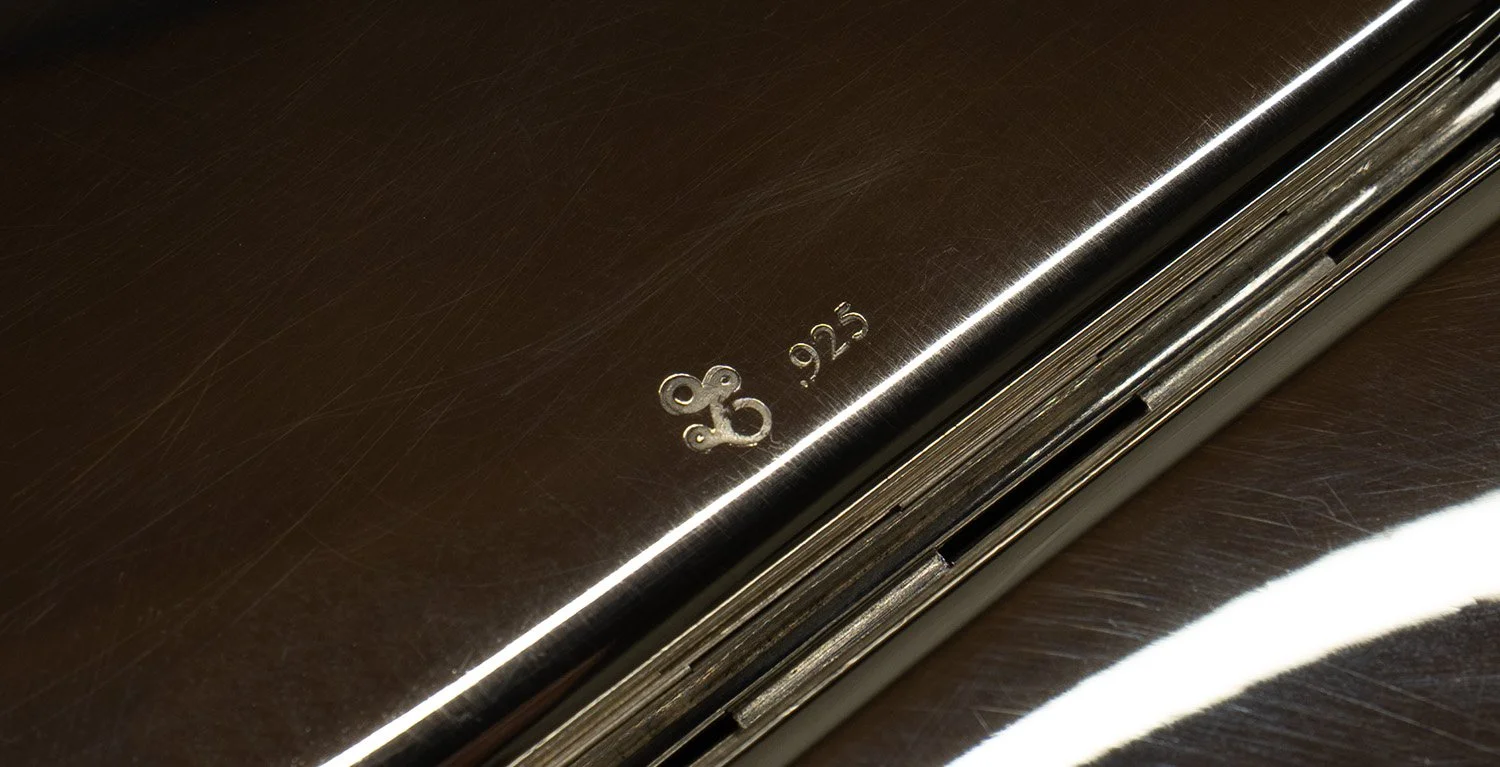 Close-up of a silver surface with engraved markings '.925' indicating sterling silver, and the Et Collective stamp.