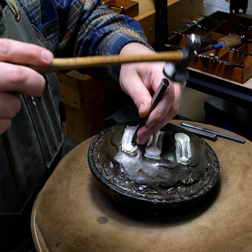 A metalsmith within the Et Collective LLC collaborative works on a component of an Et Collective object in the workshop.