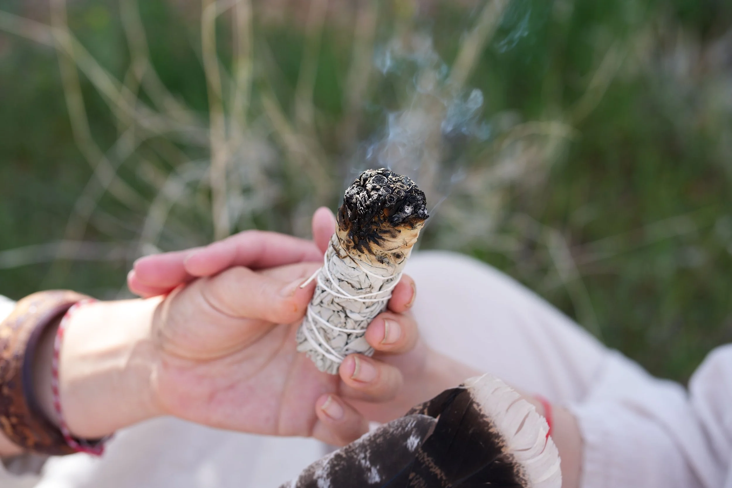 Close-up of Silviya Doneva holding a bundle of sage, representing healing, reflection, and spiritual practices through The Butterfly Alchemy.