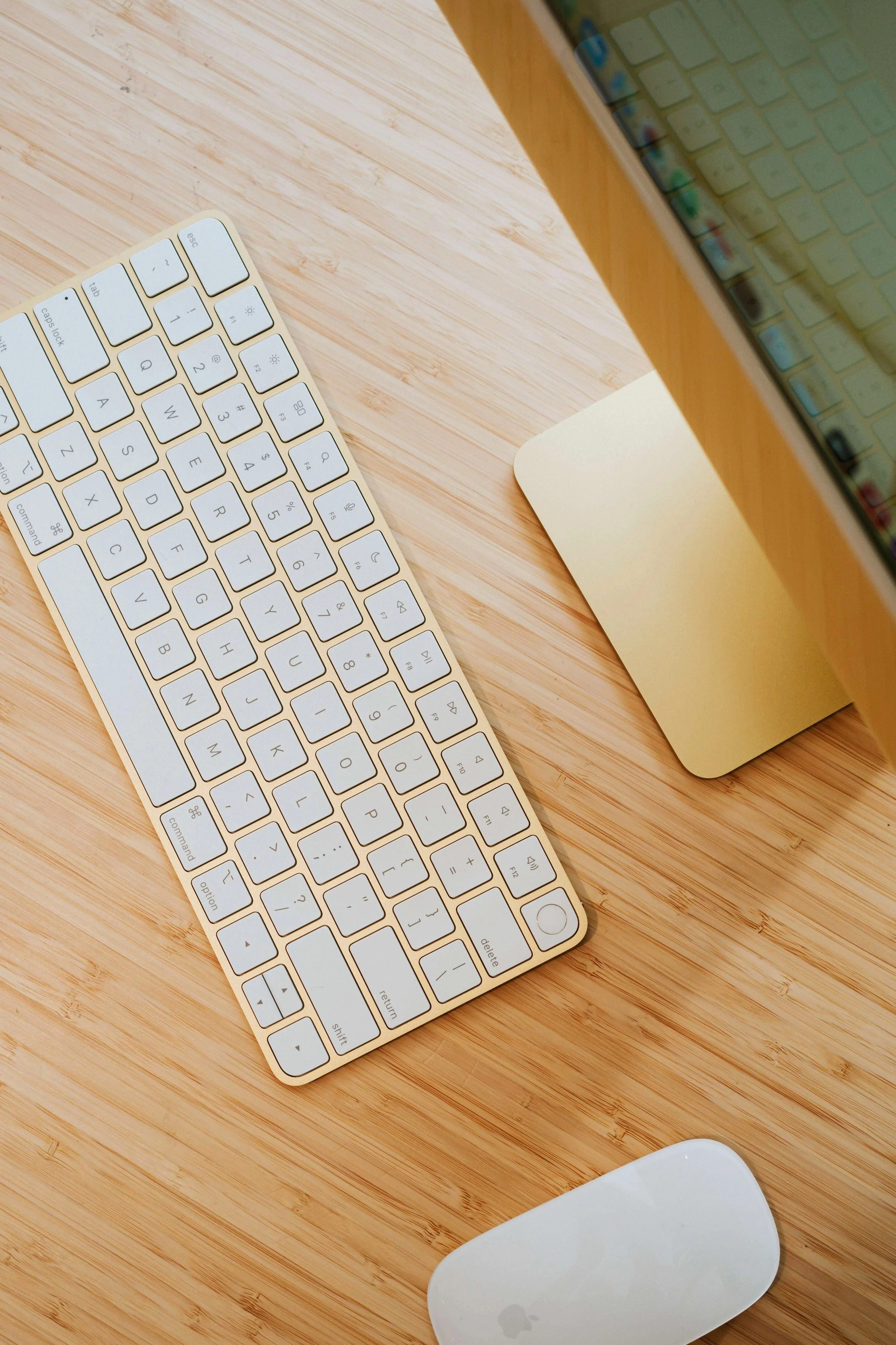 Top-down view of a wooden desk with an Apple wireless keyboard, a Mac mini computer, and a white mouse.