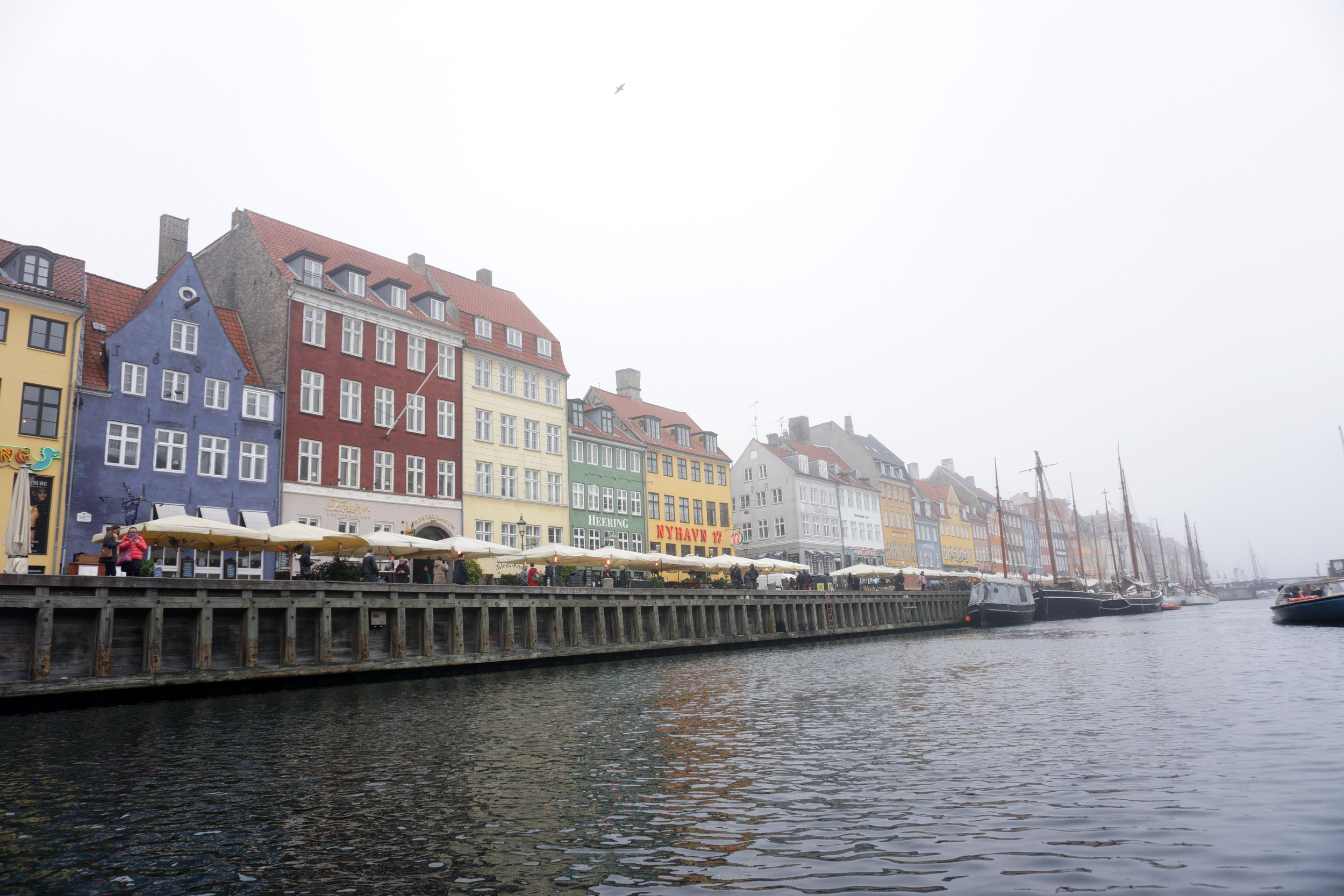 Colorful buildings along a waterfront with boats docked on the water, overcast sky.