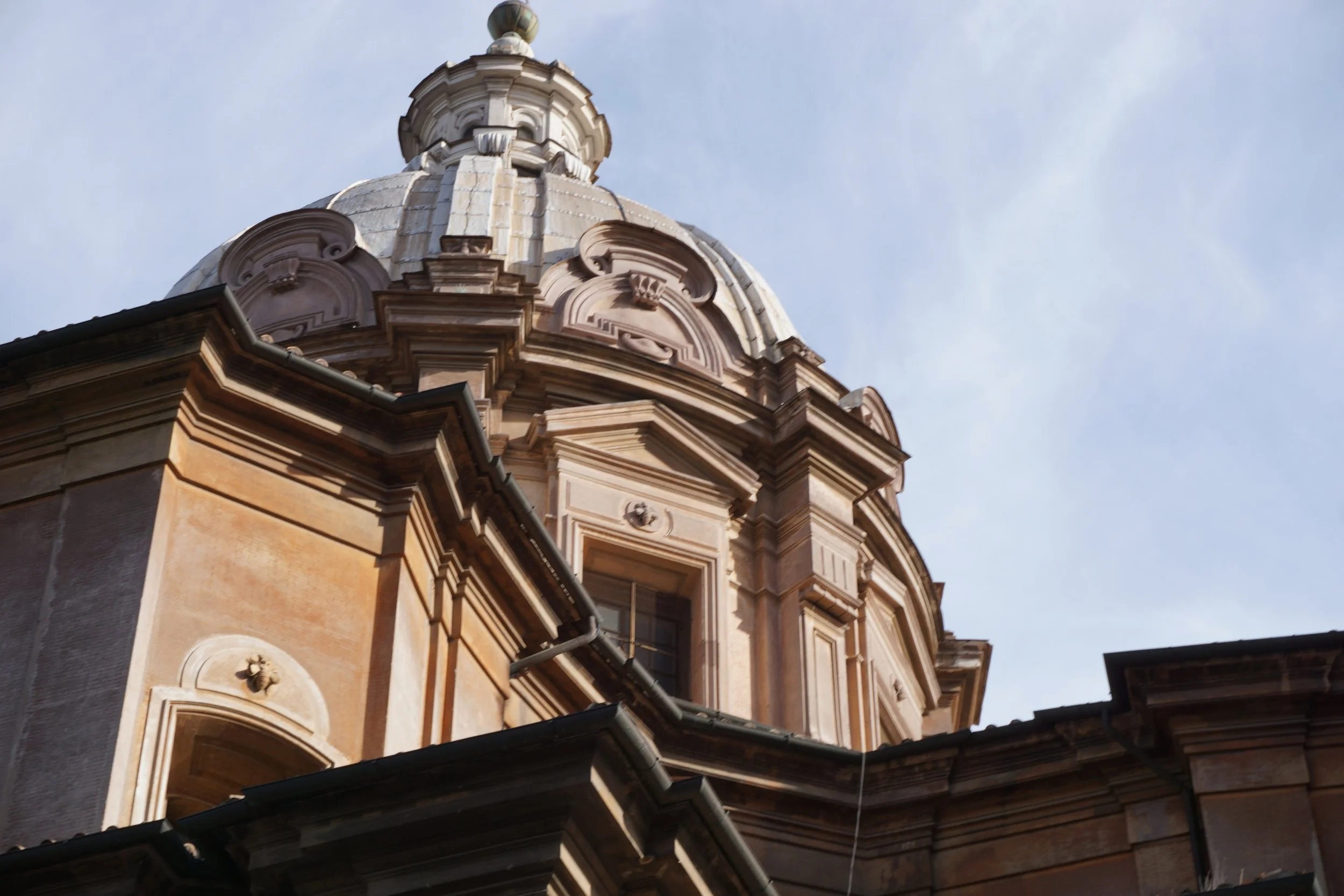 Close-up of a classical architectural building's dome with ornate details, against a clear sky.