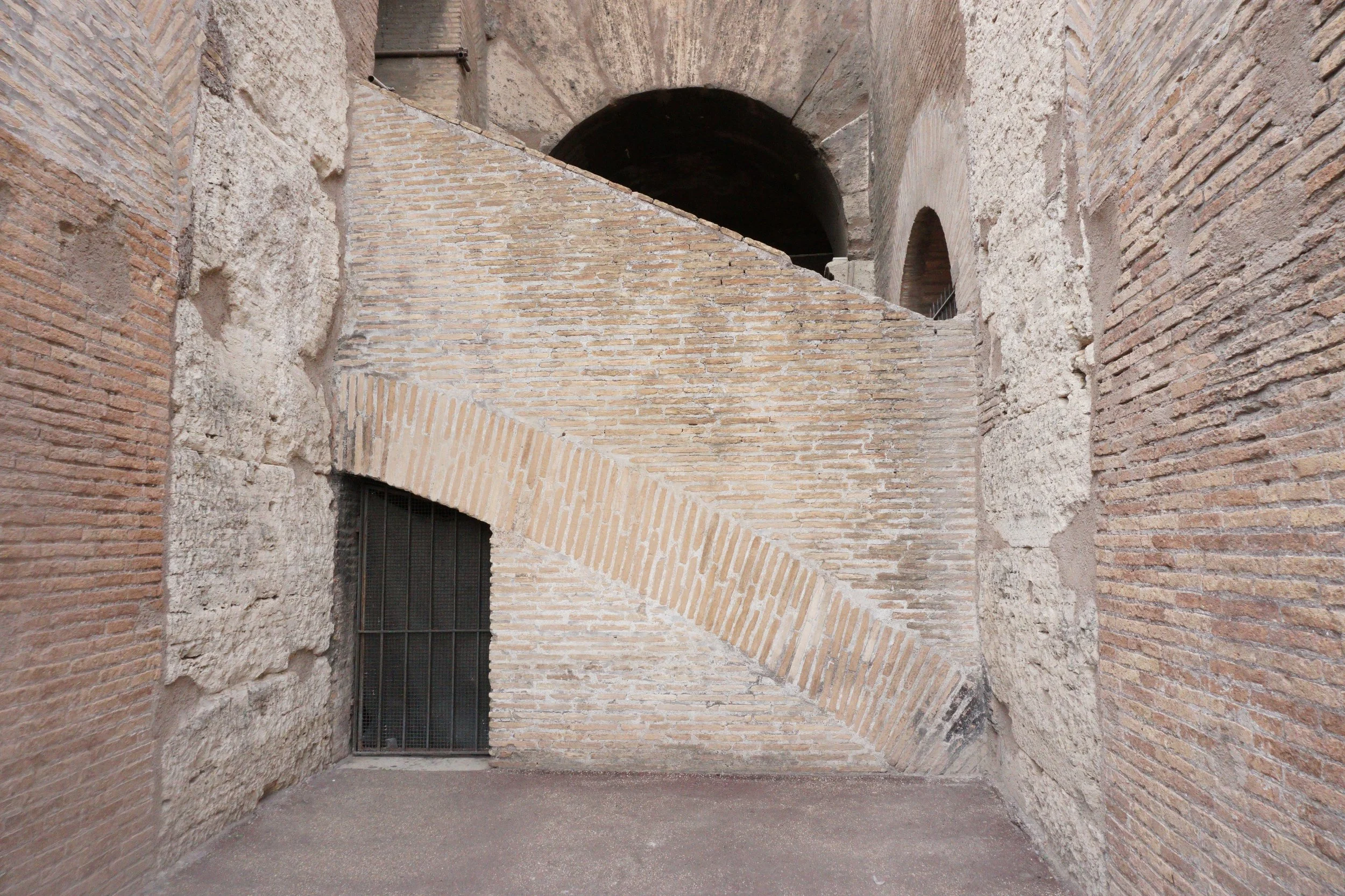Photo of ancient stone and brick walls, with a sloped brick structure in the middle, part of an archaeological site or historic ruins.
