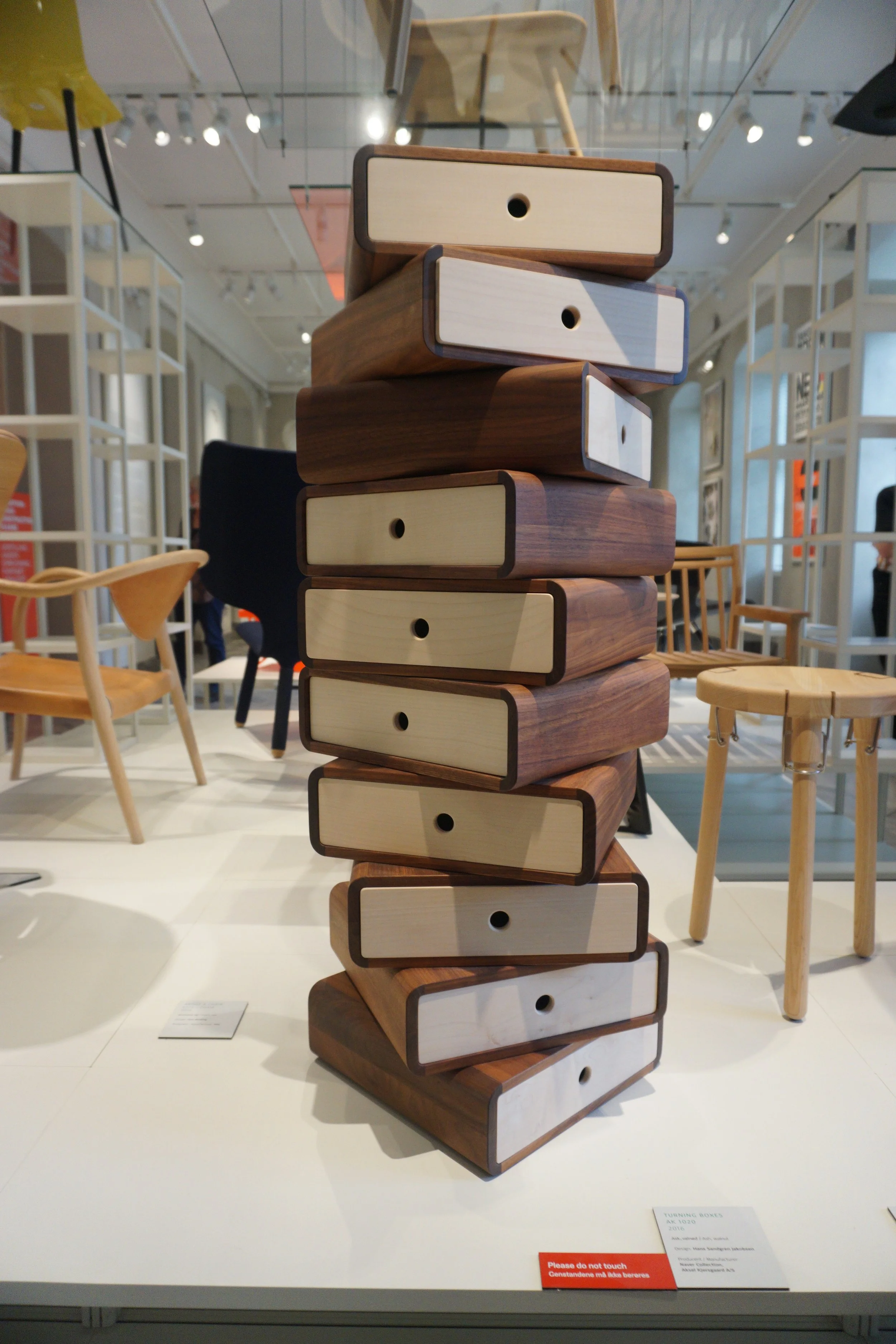 A tall wooden stacking storage unit resembling a tower of numbered drawers, displayed in a furniture store.